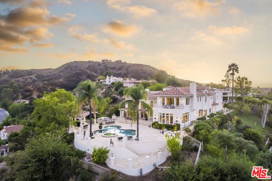 Step into an unparalleled residence that flawlessly marries bespoke elegance with a reimagined, modernized allure. Introducing The Gates at Ariella, a beacon of bespoke luxury within Calabasas Park Estates, showcasing over 7,200 square feet of light-infused opulence. This architectural masterpiece, bathed in natural light, boasts five generously proportioned bedrooms and six baths. Ascend to the pinnacle of luxury in the primary suite, a high-altitude sanctuary offering a sprawling living space, a spa oasis, and a bespoke walk-in closet worthy of admiration. As you enter through the towering foyer, be greeted by a luminous expanse that seamlessly connects all living areas. The palatial living room is a symphony of space, featuring soaring ceilings, a modern precast fireplace, and floor-to-ceiling windows bathing the room in natural radiance. The family room, an inviting retreat, embodies luxury with its entertainment bar and panoramic views of the serene grounds. A chef's dream, the kitchen exudes warmth and style, adorned with custom finishes and a seamless flow to a charming bistro patio. A testament to modern refinement, discover a custom wine cellar adorned with modern-lit onyx accents and bespoke paneled doors. Car enthusiasts will revel in the four-bay garage, equipped with two custom car lifts. Outside, an entertainer's oasis awaits a multitude of seating areas, a patio casita with built-in heaters, and an outdoor kitchen boasting top-grade amenities, all enveloped in beautiful mood lighting and a state-of-the-art sound system, ideal for hosting unforgettable gatherings. Nestled behind its privately gated flag lot within the guard gates of Calabasas Park Estates, this residence epitomizes a tailored opulence reimagined for modern luxury connoisseurs. Welcome to a harmonious blend of timeless sophistication and contemporary allure.