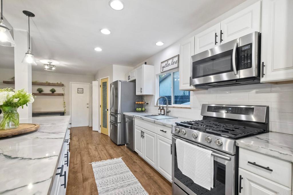 Located in a cul-de-sac, in walking distance to schools, parks, and minutes away from freeways this home is move-in ready. Step inside and you’ll find fresh interior paint, brand-new carpet with premium spill-safe padding in 2 bedrooms, modern lighting fixtures, and elegant quartzite countertops paired with Samsung kitchen appliances. A spacious walk-in pantry, indoor laundry, and EV charging plug add both convenience and modern functionality. HVAC installed in 2019. Water heater is 1 yr old. The interior shines with newer Pergo laminate flooring, natural stained beams, an ethanol fireplace, and designer touches like a shiplap accent wall in the master suite, double mirrored sliding barn doors, and custom built-in closets. The bathrooms have been updated with newer toilets, tubs, showers, and vanities, blending style with comfort. The backyard is designed for entertaining and everyday enjoyment with a custom Santa Maria grill, a built-in daybed swing, a cozy gas fire pit, and lush landscaping featuring lime and plum trees, birds of paradise, and stately palms—all enhanced by landscape lighting and an in-ground irrigation system. A semi in-ground pool with composite decking completes this outdoor oasis, offering the perfect place to relax and soak up the California sun. Located close to freeways, dining, and amenities, yet offering the privacy and serenity of a retreat, this home combines modern upgrades with timeless charm. With so many features already in place, all that’s left to do is move in and enjoy in style.