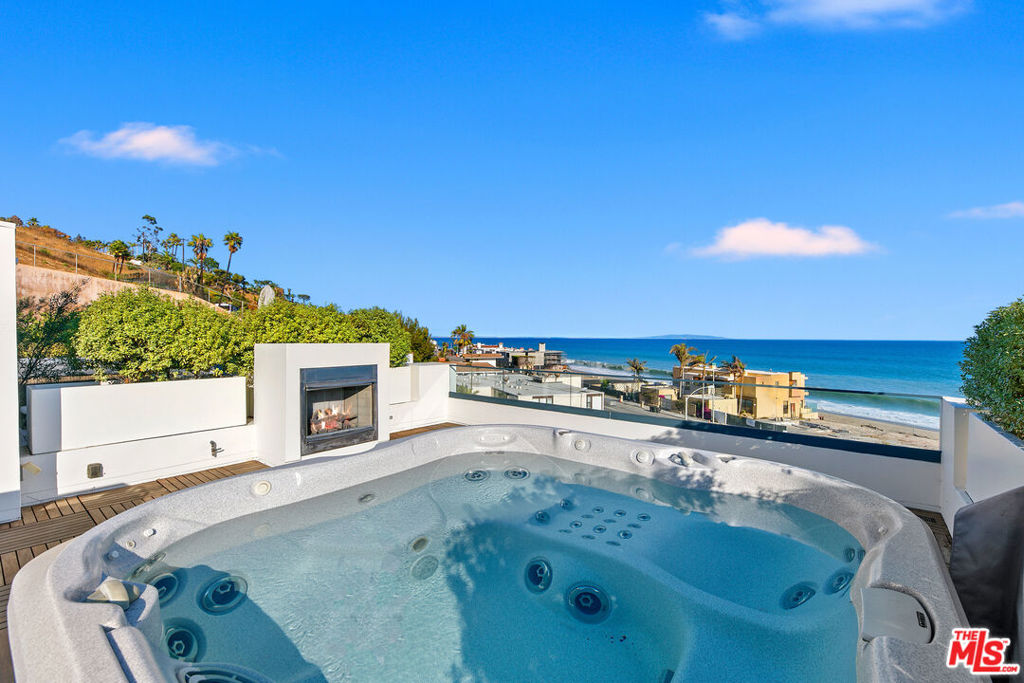 Experience the ultimate Malibu lifestyle at this ocean-view retreat in the exclusive Residences at Carbon Beach, just steps from Billionaire's Beach. Residence #7 is one of only eight homes, offering modern elegance, soaring ceilings, and abundant natural light throughout. Enjoy sweeping ocean views from every level, including the rooftop terrace with an 8-person spa and entertaining space. The main floor features an open layout with a chic breakfast nook, chef's kitchen with marble counters, top-tier appliances, dual dishwashers, prep sink, and wine fridge. The living room flows seamlessly to a private balcony for indoor/outdoor entertaining.Upstairs, the ocean-view primary suite boasts a private balcony and spa-like bath. Two additional en-suite bedrooms, a spacious sitting room, and laundry complete this level. Modern conveniences include a private elevator, and dual 2-car garages with bonus room. Located moments from Nobu, Soho, Malibu Farm, and more, this rare property blends luxury, privacy, and convenience in one of Malibu's most coveted settings.