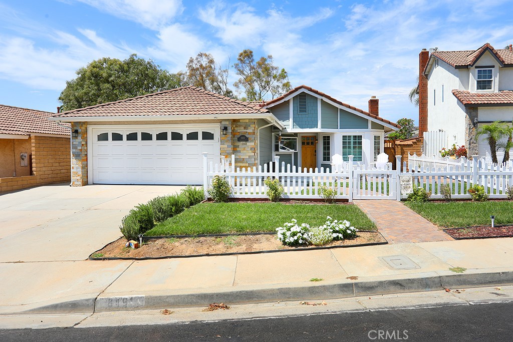 Dreaming of the perfect home with a white picket fence? Here it is! Delivering charm and sweeping city light and mountain VIEWS, this SINGLE STORY 3 bed 2 bath home tucked away in the Bel Air neighborhood of Anaheim Hills offers a a sense of tranquility and vibrant energy all at once. Delightful curb appeal welcomes you up a newly paved and enclosed front patio for extra outdoor entertaining. Inside discover a cozy family room with vaulted ceilings, rich brick fireplace with custom mantel and a picture perfect bay window trimmed in classic plantation shutters. The newly remodeled farmhouse kitchen is accented with crisp white shaker cabinetry, quartz counters, glazed subway tile backsplash, stainless steel appliances, a deep single basin sink, recessed lighting and features a light-filled window box. Head down the halls trimmed in wainscoting to the primary bedroom with vaulted ceilings and impressive views overlooking the rolling hills and direct access to the backyard. The enviable remodeled primary bath features a walk in shower with artful tile work and a custom glass enclosure and dual vanities with granite counters. Two ample sized guest bedrooms share a guest bath with single vanity and granite counter. Outdoor entertain under the covered patio outfitted with electrical lighting or perfect your golf game on the putting green while soaking in the incredible views. The garage features epoxy flooring, upgraded lighting, new cabinets, a custom entertainment center with TV and attic storage with pull down ladder. Other improvements include a newer water heater, HVAC system, gutter system, whole house fan, interior and exterior paint, low maintenance turf, exterior hardie plank concrete siding and new stone facade. This low HOA neighborhood offers convenient access to 91 and 241 freeways, shopping centers, dining, hiking trails, award-winning schools and more!