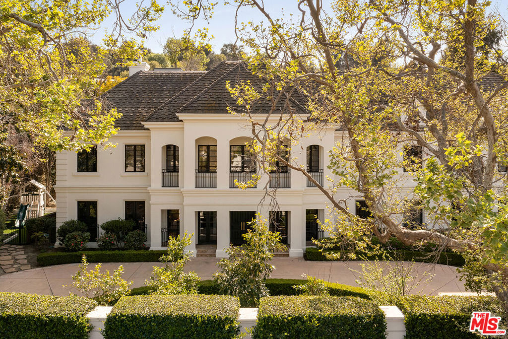 Set behind gates on one of the most sought-after streets in Longridge Estates, this grand corner-lot residence sprawls over a nearly 2/3-acre flat, usable lot. Offering over 10,000 square feet of thoughtfully curated living space, this estate was completely renovated in 2020, and is surrounded by mature landscaping, privacy hedging, and a sweeping circular drive with an additional motor court. Elegance is immediately established by the dramatic double staircase in the entry foyer, leading into a light-filled formal living room with soaring ceilings and windows beautifully framing the outdoor grounds beyond. A custom wet bar, fireplace, and gallery-style wall space create a natural rhythm for entertaining or quiet repose. Just beyond, a secondary family room centers around a limestone fireplace, offering a warm and relaxed atmosphere while maintaining connection to the larger entertaining spaces.The chef's kitchen opens from the formal living area and is anchored by a large center island and breakfast bar, appointed with multiple Sub-Zero refrigerators, a Viking range, and a walk-in pantry. It's a space designed for ease and function, seamlessly supporting both daily life and large-scale hosting. Adjacent, the formal dining room is lined with wooden French doors that open to lush outdoor vignettes, blending contemporary sophistication with a soft connection to nature.The primary suite serves as a true retreat, featuring a private sitting lounge and fireplace, overlooking the backyard through wooden French doors. The en-suite bath is impeccably finished with dual vanities, a soaking tub set inside a marble-encased shower, and black steel details that lend a refined architectural edge. A generous walk-in closet completes the suite. Each additional bedroom includes its own en-suite bath and walk-in closet, offering privacy and comfort for family or guests.Additional interior spaces include a richly toned office with coffered ceilings and sitting lounge, a fully equipped gym, and a newly built upper-level attic that adds a dramatic recreation floor. Here, vaulted ceilings with exposed beams, multiple skylights, a striking custom bar, and living room with fireplace create a flexible space for lounging, games, or entertaining. A separate game room, bonus room, and additional bathroom add even more versatility.Across the motor court, a detached three-car garage is topped by a fully realized home theater with its own library nook, lounge, snack station, and bathroomideal for screening nights, creative work, or relaxed evenings in. Outdoors, the grounds are beautifully composed with a saltwater pool and spa, full bar with built-in BBQ, and a shaded patio with a permanent structure and skylights, plus a gas fireplace. A sports court, pickleball court, and bocce area are tucked into the landscaping, while a wide flat lawn invites recreation and gathering, surrounded by fruit trees. Equipped with a state-of-the-art Control4 system, this home artfully balances volume with calm, offering not only architectural presence but also a location of true conveniencejust moments from Sherman Oaks' premier dining, shopping, and recreational offerings, with effortless access to Beverly Hills, major thoroughfares, and top-tier school districts.