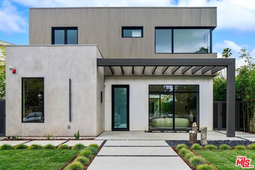 Presenting this newly completed contemporary entertainer's home, gated and set back from a wide tree-lined street in a desirable northeast Santa Monica neighborhood. Thoughtfully placed drought-tolerant landscaping lines the perimeter as lush green grass complements the home's architectural facade. Rows of bamboo contribute to a serene, zen-like environment. Inside, barn doors slide to reveal a glass-enclosed living room with stone fireplace and modern chandelier, perfect for hosting guests and quiet conversation. The nearby guest bedroom can also be used as an office or study. White oak floors flow throughout the great room, from sitting area to dining and onward to the home's culinary center. The kitchen is equipped with custom refrigerator, chef-grade Wolf range with hood, sleek cabinetry, shimmering tile backsplash, porcelain counters, and center island with wine fridge and bar seating. Multi-slide doors open to maximize the courtyard for a coveted California indoor-outdoor lifestyle. An additional first-floor bedroom accesses the courtyard through sliding glass doors. Upstairs, an impressively expansive landing leads to a loft with built-in writing desk and cabinetry. The spacious primary suite continues the home's architectural design and features a kitchenette with elegant open shelving. Its en-suite bathroom is a beautiful spa-inspired retreat, with inspiring terrazzo tile floors, soaking tub set against a double-size rainwater shower, and dual-sink vanity. There are also two large walk-in changing closets with custom built-ins and a private balcony overlooking the entertainer's courtyard below. Three other light-filled bedrooms and bathrooms are outfitted with fine finishes and on-trend fixtures. One of these secondary bedrooms has its own balcony overlooking the courtyard. Designed and constructed with entertaining top of mind, the courtyard provides plenty of room to lounge and stretch, dine al-fresco, barbecue, and dazzle party guests. There is also a grassy play space and rear motor court, all secured by a motorized gate. Welcome to a fantastic, fresh lifestyle near parks and schools, just moments to the area's boutiques, shopping, fine dining, beaches, freeways, and the many reasons that make the Westside a wonderful place to call home.