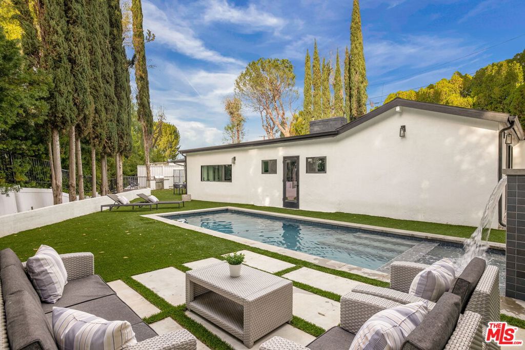 Located in the heart of Encino, this updated contemporary home sits at the end of a long semi-private driveway for privacy and seclusion. Recent upgrades include HVAC, electrical, and pool systems, all within a top-rated school district. The dining area features vaulted ceilings with skylights and a brick fireplace, opening to the kitchen. The home offers 3 bedrooms, including two with en-suite baths, multiple living areas, spa-style bathrooms, and a dedicated laundry room or pool house. The expansive, private outdoor space features a pool, spa, oversized cabana, fire pit, and outdoor screening area ideal for entertaining, relaxing, and enjoying the Southern California lifestyle. Close to top dining, shopping, and entertainment on Ventura Blvd.