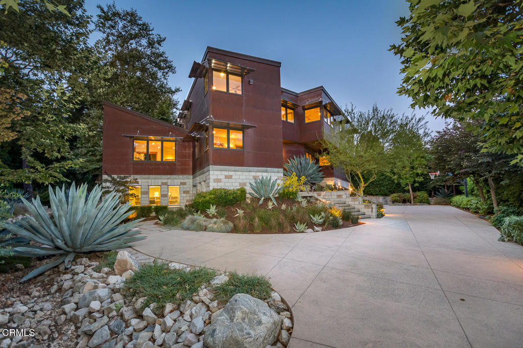On the market for the first time since its conception, this extraordinary three-level estate was thoughtfully designed & built by its original owner, a professional architect. Set at the end of a long, gracious private driveway, the home blends sculptural form, enduring materials, seamless indoor-outdoor flow. Constructed with copper, concrete, Douglas Fir, commercial-grade systems, it offers visual distinction & long-term performance. A custom laser-cut stainless steel front door trimmed in exotic hardwood opens to interiors framed in Douglas Fir, where a floating copper 'cloud' conceals ductwork above the main hallway. The main level features a dramatic living room with soaring ceilings, acoustic slats, asymmetrical windows, & a cast-in-place concrete fireplace. Above it, the copper 'cloud' continues, concealing the flue & reinforcing the home's sculptural theme. The kitchen is both functional & refined, equipped with granite slab counters, two dishwashers, double ovens, a warming drawer, an oversized fridge & freezer, built-in trash drawers, & a walk-in pantry. A marble-topped buffet anchors the formal dining area, while the open family room offers built-in shelving & a copper-topped desk. Both rooms open to a covered patio & landscaped yard. A versatile bedroom or office & a guest bath complete the main level. Upstairs, the primary suite offers treetop views, a walk-in closet, & a spa-style bath with granite slab surfaces & a glass-block-accented walk-in shower with dual shower heads. Three additional bedrooms include a junior suite & two joined by a Jack-and-Jill bath. Skylight wells enhance natural light & airflow. The laundry room includes generous storage, a utility sink, & roof access via an integrated ladder. The daylight basement includes a three-car garage--an oversized two-car bay with ample room for storage & maneuvering, & a separate single-car garage used as a workshop with 220V outlets & compressed air lines. Adjacent is a large, finished multi-purpose suite with its own HVAC system, private entrance, & half bath. Originally designed as the architect's office & currently used as a gym, the space offers flexibility for a guest suite, studio, or potential ADU. Additional highlights include: elevator to all levels, copper plumbing, fire sprinklers, Loewen windows, central vacuum, multi-zone HVAC, & carbon-based water filtration. This rare architectural offering was built to creatively combine form, function, & beauty.