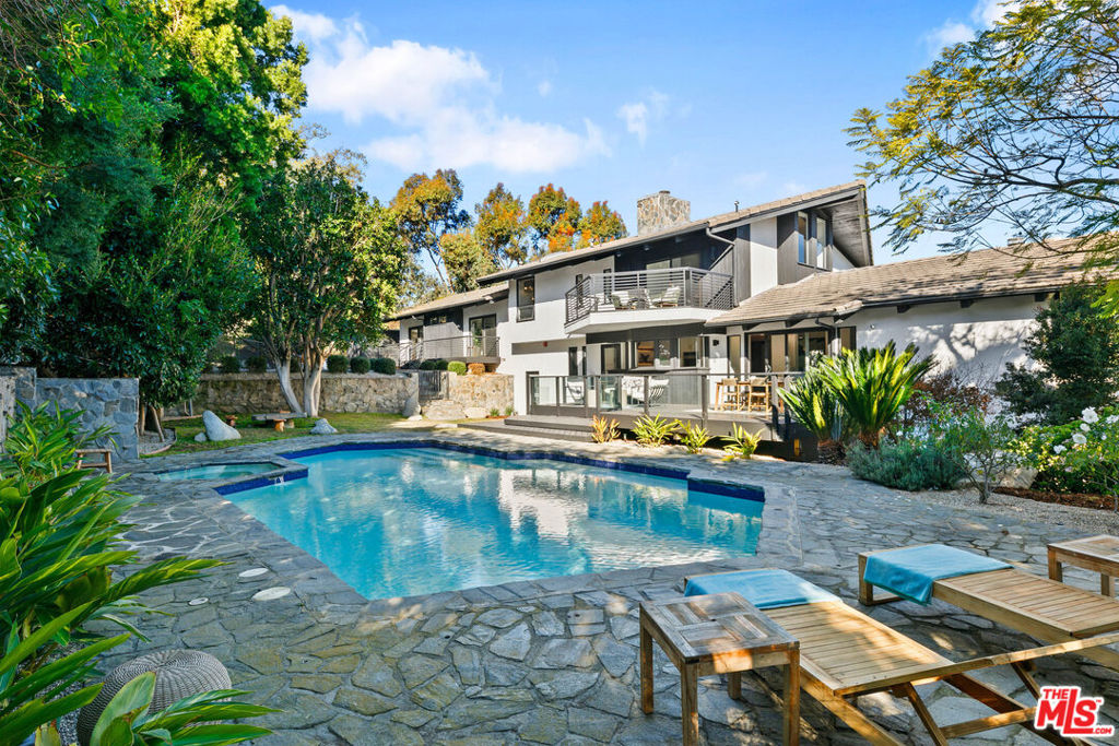 Situated in the coastal oasis of Malibu Park, this remarkable estate offers the finest points of Malibu living with a verdant setting and unparalleled privacy. Spanning over 2.5 lush acres and completely enclosed, the park-like atmosphere boasts a pool/spa, sprawling lush lawns, mature trees, and a private orchard. At the center of the property, a freshly updated modern ranch home features impressive square footage, combining private retreats with grand areas perfect for entertaining. Luxury finishes are found throughout the home, including refinished wood floors, recessed lighting, and soaring beamed ceilings. Upon entry, the open-concept floor plan allows for seamless flow, featuring an expansive living room with a large fireplace and walls of glass that open onto a balcony with ample room to dine or lounge. A connected den offers a second fireplace and balcony and transitions effortlessly to a dining area and Chef's kitchen complete with white quartzite countertops, a large dine-in island, and luxury appliances. Sliding glass doors lead to a backyard deck and a large pool/spa surrounded by flagstone, lawns, and mature trees. On the second floor, there are three bedrooms and two jack and jill bathrooms, plus a seating area and fourth room perfect for an office or home gym. The primary suite occupies the entire upper floor, boasting a fireplace and picturesque vaulted ceilings with a balcony overlooking the pool. The luxurious en-suite bathroom is a sanctuary, complete with an open shower, soaking tub, and a generous walk-in closet. On the lower level, an attached guest studio with private outdoor access and en-suite bathroom provide an ideal space for guests or a small rental unit. There are countless outdoor areas perfect for entertaining or expanding, including a fruit orchard perched on the knoll above the home offering a rare opportunity for farm-to-table living. Ample parking is available in the roundabout driveway and 3-car garage equipped with a universal car charger outlet. Located minutes from Zuma Beach, enjoy easy access to Malibu's widest, sandiest beach and most consistent surf break, as well as the local markets at Point Dume and Trancas. A home of this size and location is truly unmatched, making it an extraordinary retreat for those seeking privacy, luxury, and the essence of coastal living.
