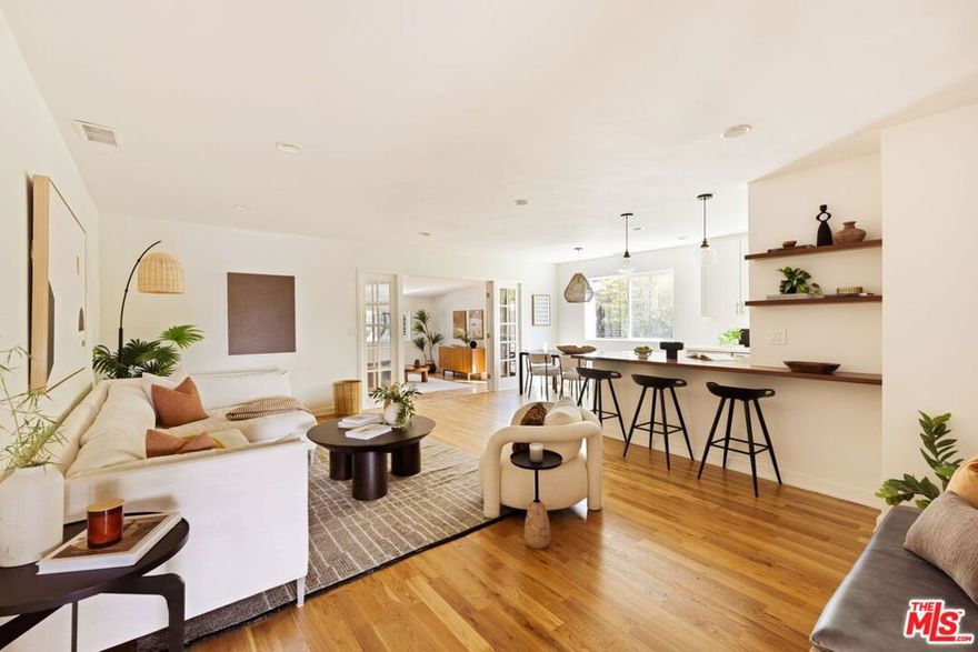 Set in the hills of Glassell Park, this midcentury traditional home reflects the easy character and creative spirit of the Eastside. Thoughtfully renovated inside and out, it offers a creative, welcoming environment with a sense of style that feels distinctly its own. Inside, the main living spaces open naturally to one another, with light filtering through broad windows and soft views of the garden outside. The living room is anchored by warm hardwood floors and custom built-ins that lend an authentic midcentury feel. Through a set of French doors, the family room extends the space even further into an airy, roughly 400-square-foot retreat centered around a vintage 1960s wood-burning fireplace. It's a place that naturally becomes the backdrop for relaxed evenings, from movies to good conversation and quiet moments by the fire. The kitchen and dining area share a clean, contemporary sensibility. Custom cabinetry, a walnut peninsula, and stainless steel appliances create a visual balance. The layout encourages gathering, with generous counter space for cooking and seamless flow to the outdoor patio. Soft, neutral finishes highlight the light and craftsmanship that define the home's design. Each bedroom includes a custom closet system, and all three bathrooms have been updated with concrete tile and clean, modern finishes. A private side entrance leads directly to one bedroom and bath, ideal for a guest suite or home office. Outdoors, the yard feels like a hidden garden surrounded by olive trees, rosemary, lavender, jasmine, roses, and succulents. Three connected alfresco lounges with built-in seating and Sunbrella shades create inviting areas for relaxing, dining, or entertaining. Each has its own character, with one ideal for coffee, another for shared meals, and one that feels like a hideaway for you and a good book. Dappled sunlight filters through the trees, bringing warmth and movement to the space as the garden hums with color, scent, and the quiet flutter of hummingbirds and butterflies. An oversized  two-car garage and brick driveway offer ample parking, while the front porch frames views of the Hollywood Sign, Griffith Observatory, and the glow of sunset over the hills. Turnkey and full of personality, this home offers a natural rhythm of indoor-outdoor living close to neighborhood favorites including Dunsmoor, Wife & Somm, Bub and Grandma's, Kumquat Coffee, Joy, and Triple Beam Pizza, with quick access to major freeways and everything the Eastside has to offer.