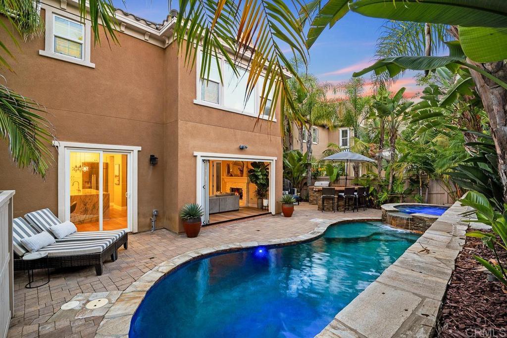 5-Bedroom Pool Home with Designer Upgrades! This stunning entertainer’s retreat offers true California indoor/outdoor living with a sparkling pool and luxurious upgrades throughout. Tucked in the highly desirable Venzano community near San Elijo Hills, this 3,437 sq ft home is a must see! Step inside to find a recently remodeled modern kitchen, new luxury vinyl plank flooring upstairs, updated lighting & fixtures, new windows, and owned solar. The chef’s kitchen is a showstopper with white shaker cabinetry, soft-close drawers, Quartz double waterfall island, custom pendant lighting, herringbone backsplash, and high-end appliances—including a Dacor built-in fridge, range/oven with custom hood, double ovens, Bosch dishwasher, wine fridge, and appliance garage. A spacious butler’s pantry with a second wine fridge and walk-in pantry adds abundant storage. La Cantina doors open wide to a private backyard oasis featuring a pool with Baja shelf, spa with waterfall, built-in BBQ with outdoor fridge, and lush tropical landscaping anchored by a Canary Date palm. Perfect for entertaining or relaxing with the ocean breezes. The versatile floor plan includes 5 bedrooms, 4 bathrooms, an office, and loft. The main level offers a full bed and bath, large living/dining combo, and office with custom built-ins. Upstairs you’ll find 4 additional bedrooms, 3 bathrooms, a loft, and a generous primary suite with dual closets, jetted tub, and oversized shower. Additional highlights: solar for house and pool, A/C, tankless water heater, laundry room, and a 2-car garage with storage. Exterior features include a Dutch door entry, stamped concrete driveway, and mature, tropical landscaping. Enjoy the Venzano neighborhood, known for its quiet, wide streets, tot lot, and sense of community. Walk to San Elijo Elementary and Middle Schools, zoned for popular San Marcos High, and just steps to Questhaven Park, 18 miles of hiking and biking trails, and the vibrant town center with shops, dining, and sports fields. Modern upgrades and resort-style living!