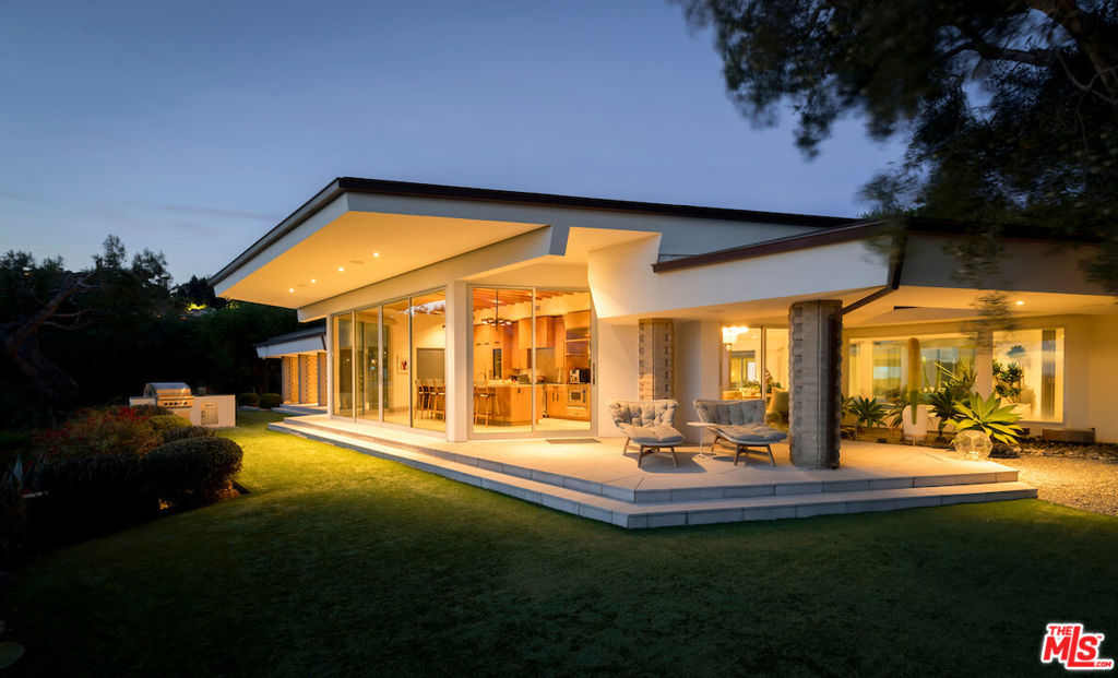 The Robby Krieger Estate, Bel Air. A Mid Century masterpiece tucked away on an ultra private 1.4 acre view lot in lower Bel Air. Meticulously crafted by Matthew Leizer for legendary rockstar, Robby Krieger of The Doors, this single story residence was expertly restored with the utmost, keen attention to detail, seamlessly blending the architecturally significant elements with modern elegance. Set back behind gates down a long driveway and framed by mature landscaping, a sweeping motor court dramatically meets this hexagonal-shaped abode. Guests are welcomed by Terrazzo floors, double height vaulted corked ceilings, and an abundance of sunlight pouring in through the floor to ceiling windows. The highly functional floor plan internationally captures breathtaking views from every room including the true chef's kitchen with stainless steel appliances, generous center island, and oak cabinetry, organically echoing the surrounding natural elements. Luxurious primary suite caters to the most discerning buyer, offering dual walk-in closets, spa-like en-suite with a soaker tub and an indoor/outdoor shower, and a private patio. A serene courtyard pool is the focal point of this outdoor oasis. An outdoor dining area, barbecue, flat grassy pad, and a cozy fire pit prioritizes indoor-outdoor living. A perfect harmony of warm modernism craftsmanship and timeless grandeur.