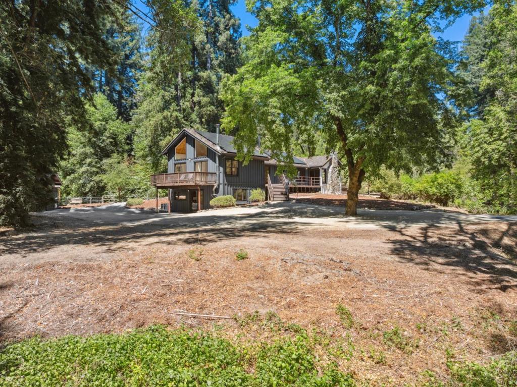 Nestled among old-growth redwoods and mature fruit trees, this peaceful Ben Lomond home offers outstanding curb appeal with a stately circular driveway, lush landscaping, and outdoor living areas. Set on around 1.5 acres of flat, usable land, the property is ideal for gardening, outdoor activities, or enjoying the open space and tranquility. Enjoy private access to Love Creek, which meanders around the property, creating a serene backdrop with the soothing sound of running water. Relax on multiple spacious decks, watch wildlife, and marvel at the stars under clear skies thanks to minimal light pollution. Inside, the home features hardwood floors, vaulted ceilings, and nearly floor-to-ceiling windows in the living room, filling the space with natural light and forest views. Luxurious kitchen cabinets add charm, while the open layout invites relaxed living. Thoughtfully updated and move-in ready, this home includes a new concrete septic tank, 11kW solar system (grandfathered into NEM 2.0), natural gas service, and 1.2Gbps high-speed internet. Tucked away from Highway 9 and located on a county-maintained road, close to downtown Ben Lomonds shops, restaurants, parks, tennis courts, trails, commuter routes, and the beaches of Santa Cruz.