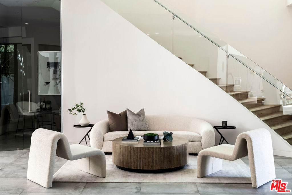 This stunning 5 bedroom, 6-bath home offers over 4,700 square feet of refined living space, where contemporary elegance meets everyday comfort. Designed with attention to detail, the residence showcases sophisticated architecture, luxurious finishes, and an effortless flow throughout. Step through the dramatic entrance into airy, open-plan living and dining spaces, ideal for everything from casual lounging to vibrant entertaining. At the heart of the home, the gourmet kitchen impresses with top-tier appliances, bespoke cabinetry, and a generous central island designed for both function and style. A sleek, climate-controlled wine room adds a touch of refinement for the avid host. Walls of sliding glass disappear to connect the indoors with a private backyard oasis. Relax in the sun-drenched pool and spa, unwind in the open-air cabana, or enjoy the multiple outdoor seating areas crafted for seamless indoor-outdoor living. Upstairs, the sunlit primary suite offers a true retreat with its own fireplace, private balcony, dual walk-in closets, and a spa-quality ensuite bath. Four additional en-suite bedrooms provide flexible space for guests, home offices, or wellness rooms. Additional highlights include multiple living areas, a formal dining room, a stylish upstairs laundry, and an attached two-car garage with direct entry. Located just minutes from Larchmont, Paramount Studios, Netflix, and the buzz of Sunset Gower and Melrose, this home is a sanctuary in the heart of one of L.A.'s desirable neighborhoods.