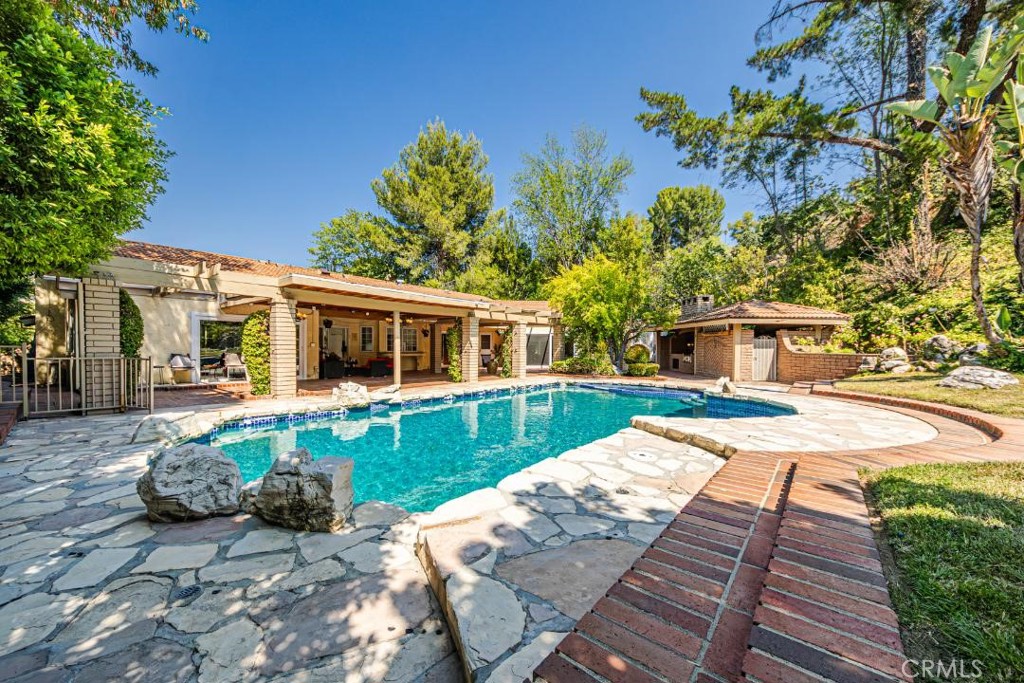 Welcome to this stunning Lake Encino home, where luxury meets serenity. As you step inside, you're greeted by the elegant marble flooring design in the foyer, setting the tone for the opulence that awaits. The spacious living room boasts high ceilings, a cozy fireplace, and a wet bar, perfect for entertaining. Large windows and sliding doors seamlessly blend indoor and outdoor living, offering breathtaking views of the lush green yard.
The formal dining room is ideal for special occasions, while the huge family room with its own fireplace is where memories are made. Abundant natural light pours in through the expansive windows, complemented by recessed lighting that highlights the home's best features. Ample storage and closet space ensure a clutter-free lifestyle.
The master suite featuring a remodeled bathroom with a designer marble shower, dual sinks, and a relaxing jacuzzi tub.
The home's layout is thoughtfully designed, with three bedrooms downstairs, each with its own bathroom, and two bedrooms upstairs. The kitchen is a culinary haven, boasting crisp white cabinets, granite countertops, and plenty of space to prepare gourmet meals.
But the true showstopper is the backyard oasis. The large flat yard is a resort-like haven, complete with a picturesque waterfall, beautifully landscaped gardens, and a spacious entertaining area. Imagine sipping coffee or enjoying a glass of wine while taking in the tranquil surroundings. The stone accents and walking path add a touch of whimsy, inviting you to explore and unwind in this serene paradise."