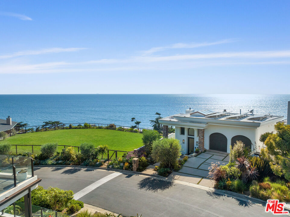 Nestled behind privacy gates of the prestigious Victoria Point community located in Malibu's famed Broad Beach area, this ocean-view masterpiece offers luxury coastal living and the unique opportunity to own two adjacent parcels of flat, lushly landscaped land! Every detail of this impeccably designed home exudes sophistication, from its fine finishes to its myriad of high-end features. The resort-style outdoor deck is an entertainer's dream, boasting a panoramic ocean view, infinity pool and spa, and a built-in BBQ area, all framed by the breathtaking coastline. Just a shell's throw to the beach, this property also encompasses two fully landscaped ocean-view lots that have been the backdrop for countless memorable family events from bridal showers to business entertaining and beyond! These additional parcels, which could also be used as your very own dog park, provide ample room for entertaining and capturing cherished moments against the breathtaking coastal scenery. Inside, discover a carefully crafted floor plan that harmoniously blends form, flow and function. The stone flooring and distinctive fireplace surround showcase the sophistication of the home. Entertain or relax with family and friends in the impressive great room with soaring beamed ceilings, picture windows, cozy media room, semi-circular ocean view bar and dining area with stacked stone accent wall. Tucked away at the rear of the room, a temperature-controlled wine cellar awaits behind a secret door. The ocean view gourmet kitchen, a chef's delight, features rich wood cabinetry and a large natural stone island with breakfast bar. The kitchen's three ovens and two distinct prep areas, each with their own sink and dishwasher, invite you to unleash your culinary creativity. The elegant and tranquil ocean view primary bedroom engages your senses with wall to wall scenic windows, cozy fireplace, beamed ceilings, large relaxation patio and spa-inspired custom bath. The walk-in closet feels more like a luxurious boutique designed with meticulous attention to detail. The residence includes two additional en-suite bedrooms, one of which is ocean facing, that are perfect for visiting guests. An office with elegant built-ins provides the ultimate professional sanctuary. The property also boasts a fully finished two-car garage with built-ins for storage and an electric car charger. A stairway to Sea Level Drive from the pool area provides access to Lechuza beach. Sitting majestically on a bluff, the home with its two adjacent parcels of land command stunning sunset views over Lechuza Beach and the iconic Malibu coastline. This rare offering presents an elegant and serene retreat that epitomizes coastal luxury by the beach. The sale of the property at 31554 Victoria Point Rd includes the following APN's: 4470-017-045, 4470-017-046, 4470-017-047 totaling approximately 26,921 square feet.
