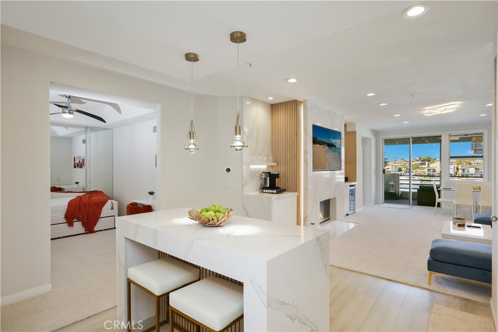Discover coastal living at its finest in this beautifully upgraded condo located in a waterfront community in Huntington Beach. This unit is located on the second floor and has serene harbor and mountain views, with high-end interior updates. It is also conveniently located near the elevator and parking spaces which are side by side. This a 2 bedroom condo has an additional den/study which was converted from the dining room to add an additional sleeping space for a third bedroom use (can add a barn door for privacy, and has room for closet space, but no window). Property has been remodeled, and uniquely designed from the other units. Property Highlights: Open-concept kitchen with marble center island, marble fire place with a marble/wood coffee station and wine refrigerator. New modern cabinets with invisible notch. The spacious primary suite feature a harbor and mountain facing layout with a large walk-in closet, dual-sink vanity with quartz counters, new bathroom fixtures, blackout curtains, soaking tub and separate shower. The secondary bedroom faces the ocean. Step outside to a private balcony which has been recently repaved with new concrete it overlooking the water, boats and the boat parade in the winter time. Recessed lighting throughout, with mood and indirect lighting and pendants. Freshly painted, new luxury vinyl flooring in the kitchen and new carpet throughout living spaces and bedrooms. Walking distance to the pet beach private boat docks for yacht club.
