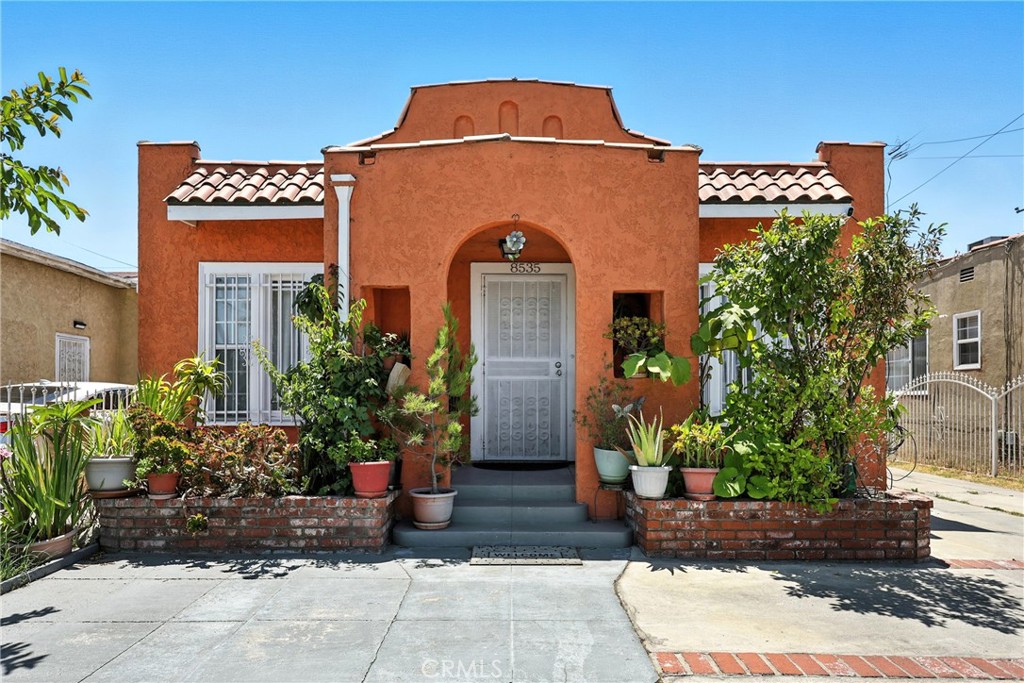 Welcome to this lovingly maintained Spanish-style home nestled in the heart of Walnut Park. Bursting with charm and character, this single-family home boasts standout curb appeal with its warm terracotta exterior, arched entryway, cozy front porch, tile roof accents, and classic brick garden borders.
A wrought iron perimeter fence offers both secure parking along the extended driveway and a safe, gated play space in the spacious front yard. Step inside to an open-concept layout where the light-filled living room seamlessly flows into the dining area and kitchen with a breakfast bar — perfect for entertaining or everyday living.
Featuring 3 bedrooms and 2 bathrooms, this home is filled with pride of ownership throughout. Highlights include beautiful tile flooring in the main living areas, an abundance of natural light, a detached 1-car garage, and a large lot.
Enjoy outdoor living year-round in the generous backyard, complete with a covered patio ideal for gatherings, relaxing, or play. With a large lot and room to grow, this charming home offers the perfect blend of style, comfort, and space. Centrally located to many schools, parks, grocery stores, local hotspots such as Gloria's, as well as 4 major freeways!