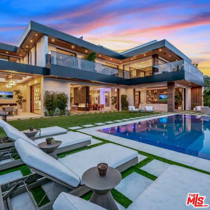 Nestled in a peaceful cul-de-sac off Tigertail, one of the most sought-after streets in Brentwood, the luxurious 950 Kenfield estate awaits. Designed and built by Ramtin Ray Nosrati of Huntington Estate Properties this contemporary masterpiece offers breathtaking vistas of the city, canyon, and the iconic Getty Museum. Bespoke finishes run throughout including an impressive array of fireplaces, stepping stone water features, and a tranquil interior waterfall making this home a true entertainer's dream. Along with the idyllic and zen environment, the chef's kitchen is equipped with custom Italian cabinetry and top-of-the-line Miele appliances. Automated Fleetwood doors allow for a seamless transition from the main living spaces to the outdoors with the infinity edge pool and panoramic views. Upstairs the airy primary suite is a true sanctuary, featuring an oversized walk-in closet and a full wrap-around balcony perfect for savoring a cup of coffee while taking in the stunning surroundings. The spa-like bathroom provides a soaking tub, waterfall shower, dual vanity and automatic shades. Three additional ensuite bedrooms round out this level. The lower level is your entertainment headquarters. In addition to an ensuite bedroom, here you find a generous gym, an impressive theater with stadium seating, a 1000-bottle wine cellar, a four-television video wall and wall and a backlit Onyx bar. Equipped with multiple Control4 tablets, this smart home enables effortless customization of the various features, including the fully integrated sound system, right at your fingertips. Additional luxe amenities include an indoor marble waterfall, cryotherapy space and a rooftop deck complete with views, sitting areas and fire pit. This home can be delivered fully furnished if desired.