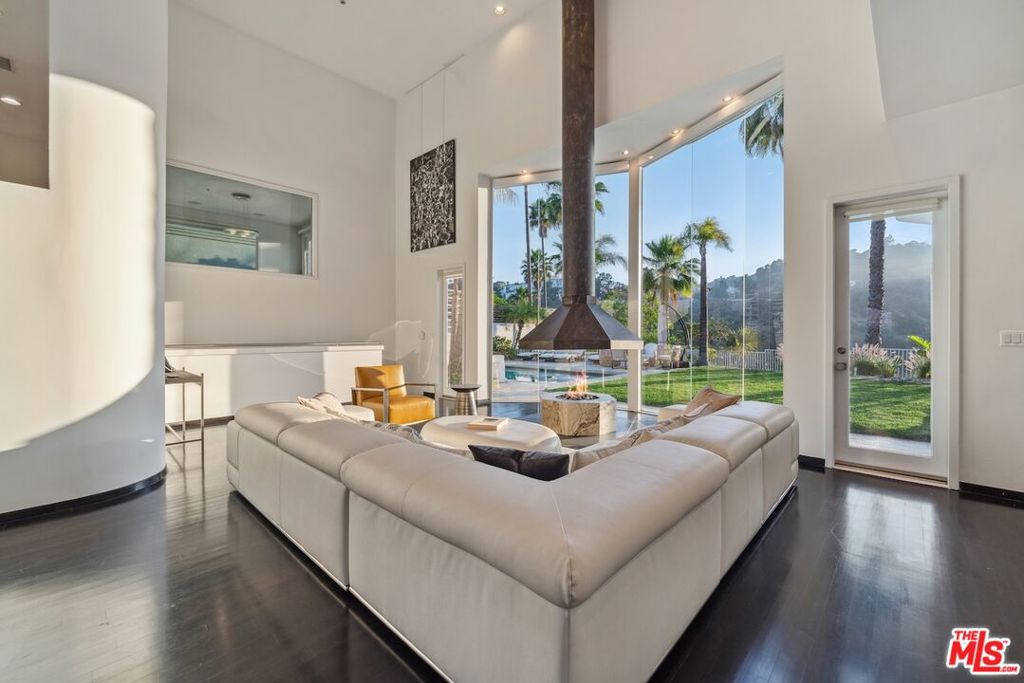 Soaring 25-foot ceilings with a dramatic curved glass wall are at the heart of this peaceful Mount Olympus home just moments from the bustling energy of West Hollywood. This striking 5-bedroom, 5.5-bath property features a sculptural central staircase leading you through expansive living and dining areas, a bold black-and-white chef's kitchen, and a cozy breakfast nook that opens to a view terrace. Each of the five bedrooms is ensuite, offering plenty of privacy and the spacious primary retreat feels like its own little sanctuary with a home office and a media lounge tucked away for cozy movie nights. Outside is a sparkling pool surrounded by lush canyon landscaping and multiple outdoor spaces made for entertaining or unwinding. Parking for 3 cars and full solar to offset power consumption, makes this not just a beautiful home but a smart and sustainable one too. Available furnished and ready now. Wifi, Basic Direct TV, ADT security/alarm monitoring and Bel Air security patrol included in lease amount.