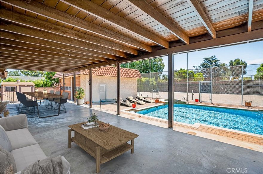 Welcome to “Old Granada Hills,” a neighborhood celebrated for its large parcels, orange orchards, and timeless charm. This is your golden opportunity to create a true family compound. Set behind gates, this expansive 3,000+ sq. ft. home rests on a flat 18,700 sq. ft. lot with an impressive 110 feet of street frontage. A gracious circular driveway leads you inside where you’ll find 5 bedrooms and 4 bathrooms, including a massive primary suite with a wall of closets and spa tub. The Chef’s kitchen is outfitted with a Viking oven, Wolf range, wood cabinetry, and abundant counter space. Multiple living and entertaining areas include a spacious living room, formal dining room, and an enormous bonus/game room—all enhanced by soaring wood ceilings, granite flooring, and oversized dual-pane windows. The cozy family room, complete with a wood-burning stone fireplace, opens to the covered patio and sparkling pool. Every bathroom is luxuriously finished in granite from top to bottom. And the pool—OMG! Unlike most residential pools, this one is fully tiled from edge to floor. Black-tile swim lanes line the bottom, perfect for training or competition. After swimming, relax in the tiled spa or lounge on the shaded covered patio. Beyond the pool lies a lighted tennis court, ideal for tennis, basketball, or even pickleball. The property also offers space for an RV, potential ADU, and a three-car garage with central I-beam—a dream setup for any craftsman or mechanic. With the 405, 5, and 118 freeways, CSUN, Trader Joe’s, and Porter Ranch shopping and dining just minutes away, the location couldn’t be more convenient. Freshly painted on the interior, it's clean and move-in-ready, Replicating these incredible improvements today would cost a fortune. After more than 60 years in the same family, this special property is ready for its next chapter. Offered As-Is by the seller’s trust. What you see is what you get—the chance to own a one-of-a-kind Granada Hills estate.