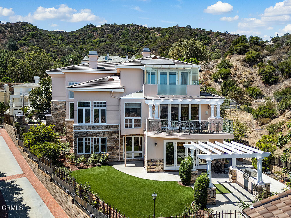 Perched high in the hills above Glendale, this custom-built 1998 residence showcases sweeping views of the lower basin and sparkling city lights. Designed with scale and sophistication, the home offers 5 bedrooms, 5 bathrooms, and two kitchens, along with an array of refined living and entertaining spaces.Spanning three levels, the floor plan blends intimacy with grandeur. Highlights include a wood-paneled library with wall-to-wall bookcases and dramatic views, a formal dining room, and a welcoming family room with a broad balcony overlooking the city. The living room is accented with Venetian plaster walls and an artist-designed stained-glass depiction of Springtime above the entry door, creating a striking first impression.At the heart of the home, the main kitchen features an oversized granite island, custom-designed cabinetry, and state-of-the-art appliances, including a Sub-Zero refrigerator/freezer, Wolf range/oven, and Bosch dishwasher. An additional kitchen offers versatility for entertaining or multigenerational living.The oversized primary suite enjoys its own view balcony and a luxurious bath with separate tub and shower. On the lower floor, an ensuite bedroom and versatile entertainment room open seamlessly to the gardens, offering an ideal indoor-outdoor flow.Outdoors, the grounds are designed for year-round enjoyment with lush landscaping, a covered patio, built-in BBQ, and tranquil gardens. A newly paved driveway enhances the home's curb appeal, while a solar power system provides modern efficiency.Inside, the extensive use of marble, granite, wood, and glass creates a timeless sense of opulence--equal parts warm and dramatic. Sited at the end of a cul-de-sac, this property offers both privacy and prestige.This is more than a home--it is a statement of elegance and comfort, perfectly suited for intimate living or large-scale entertaining, all set against a backdrop of panoramic vistas.