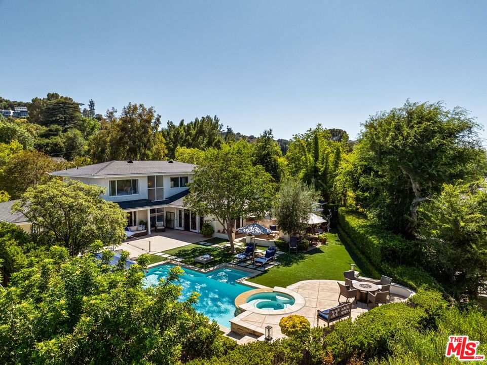 Welcome to a truly exceptional property that captures the essence of chic California living. Located in one of Sherman Oaks' best neighborhoods, this custom-designed home offers breathtaking views of Los Angeles and a meticulously crafted lifestyle rarely found on the market.Enter the circular driveway and step through a private courtyard with a tranquil fountain, creating the most inviting entrance into a home filled with character and warmth. Inside, beautiful hardwood floors flow throughout, connecting a formal living room with large picture windows and a cozy fireplace, and an elegant dining area.A striking mid-century-inspired staircase with a massive window frames your view of the expansive backyard and the city beyond. The great room features vaulted, beamed ceilings, its own statement fireplace, and an open floor plan that seamlessly connects the kitchen, family room, and a second dining area for gatherings. The kitchen is a chef's dream, with natural stone countertops, custom cabinetry, top-of-the-line appliances, and a walk-in pantry - all designed to make everyday living feel special.Every window frames a view, from the office with city vistas to the great room's expansive doors that open to an entertainer's paradise. The backyard is a true sanctuary, featuring a large flat lawn, a custom pool and spa, a stunning outdoor fireplace, and a freestanding fire pit on the upper deck - ideal for cozy evenings under the stars. Multiple seating areas are thoughtfully positioned to capture different moments of the day, while the greenery creates a lush, low-maintenance backdrop.For the ultimate retreat, there is a chic, cozy outdoor cabana for relaxation or meditation, complemented by a convenient pool bathroom. The hardscaped area, large enough for pickleball with a removable net, sits adjacent to a gym area, ensuring you never have to leave home to live your best life.Upstairs, you'll find three additional bedrooms, all with views, including a sweet primary suite with a spa-like bathroom that offers a daily escape into tranquility. This is a home made for entertaining, with exceptional energy and effortless flow, blending indoor and outdoor living in the most beautiful way. From the designer finishes to the custom details at every turn, this property is special, custom, and a place you will fall in love with.Situated within the sought-after Sherman Oaks Charter School District and in close proximity to some of LA's finest private schools, this home also enjoys easy access to the upscale shopping and dining scene along famed Ventura Boulevard. If you've been looking for a rare gem in Los Angeles that feels like your own private resort while being moments from everything, welcome home.