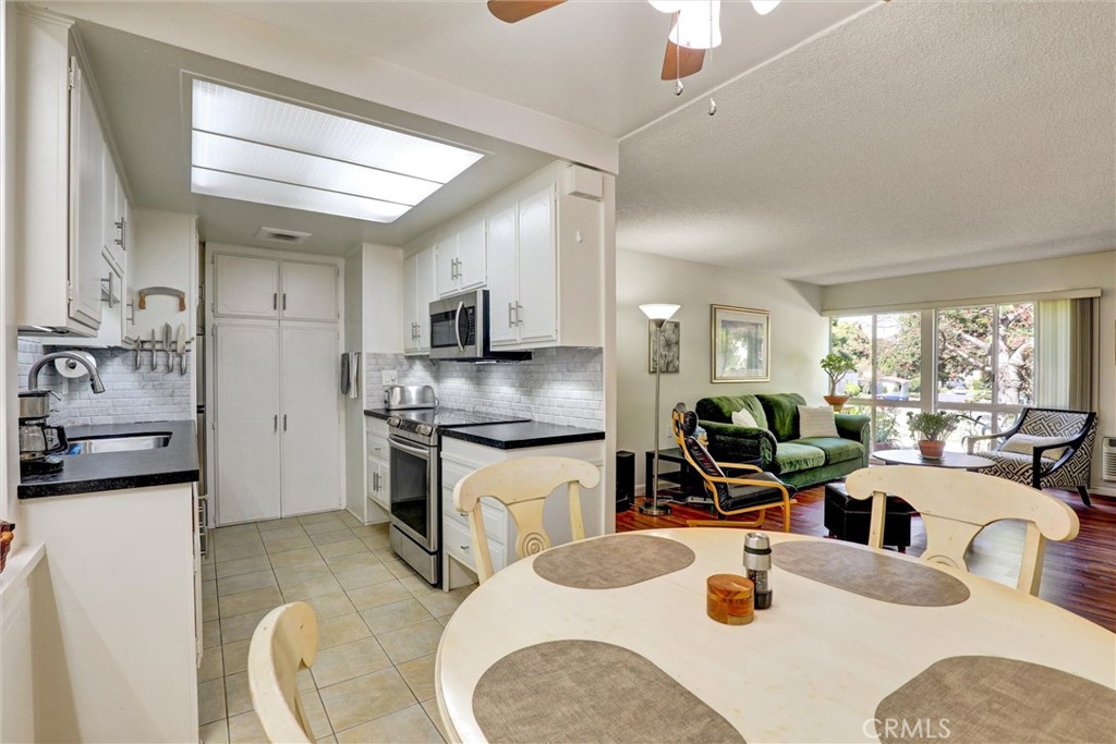 Great Location! Welcome home to Style, Comfort, Convenience, Privacy, Quiet & staying Cooler! Step into this beautifully updated and well-maintained manor where thoughtful design, details and a great location create an inviting living experience. Walk through the very large covered, shaded and private front patio---that is more like an outdoor room--and enter the front door to the spacious living room that stays cooler with natural northern light streaming through the windows overlooking the front yard and garden. Gleaming, waterproof vinyl plank floors add an easy-to-clean modern touch. The well-designed & updated kitchen is a showplace with easy-to-clean & heat resistant black granite counter tops, Italian marble tile backsplash, all stainless-steel appliances including a convenient undermount sink with an extra filtered water dispenser, a built-in vented microwave & glass-top range. Behind double doors in the kitchen is a full-sized stacked washer/dryer that's a necessary convenience & a welcome surprise! The dining room is friendly & inviting--it's main wall being carefully updated with eye-catching & modern display shelves that are ideal for showcasing your art, photos or cherished China. Both bedrooms are very well-situated on opposite ends of the floor plan for ultimate privacy and both have generous floor-to-ceiling closets. The updated bathroom has an oversized vanity, new lighting fixture and a convenient-to-enter modern walk-in shower. Go outside and enjoy the unusually large, shaded, cooler & private front patio to relax, entertain, grill or garden. A large, lockable built-in storage cabinet out there offers a handmade workbench area for tools, hobbies and also storing a bicycle if needed. Lots of curbside available street parking is a quick walk on the well-lit path right to the front door=a rare & valuable convenience in Laguna Woods! In addition there is a covered carport space with more lockable storage cabinets. As a resident of Laguna Woods Village, one of Orange County's most sought-after active adult communities, you'll enjoy resort-style living with an amazing array of amenities! Come and see the 7 clubhouses, 5 pools, pickleball, golf and so much more.