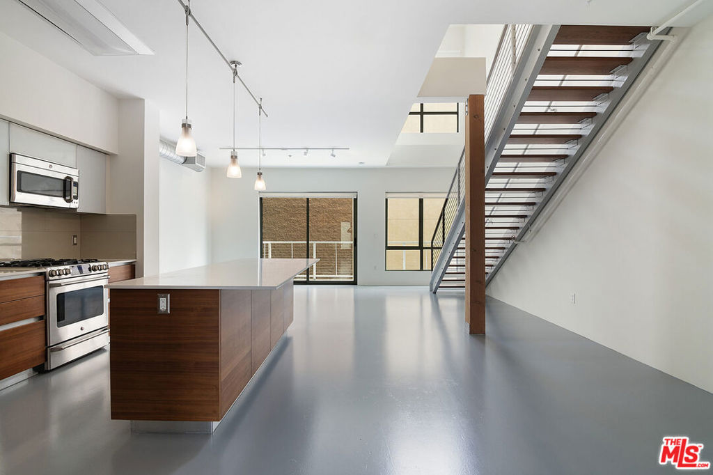 Contemporary loft living at its finest in this thoughtfully designed 2-bedroom, 3-bathroom residence located in the coveted T-Lofts community. The main level boasts a spacious open-concept layout with polished concrete floors, dramatic double-height ceilings, and a private balcony. The sleek, modern kitchen is outfitted with stainless steel appliances, soft-close cabinetry, connecting to expansive living and dining areas. A flexible den space on the main floor offers the ideal setup for a home office, creative studio, or guest nook. Upstairs, both bedrooms are privately tucked away, including a primary suite featuring a soaking tub, separate glass-enclosed shower, and a generous walk-in closet. Enjoy community amenities including a fitness center, relaxing spa, BBQ area, and beautifully landscaped grounds. The unit also includes two assigned parking spaces, plentiful guest parking, and EV charging stations. Located just moments from the vibrant Sawtelle District, local beaches, top shopping!