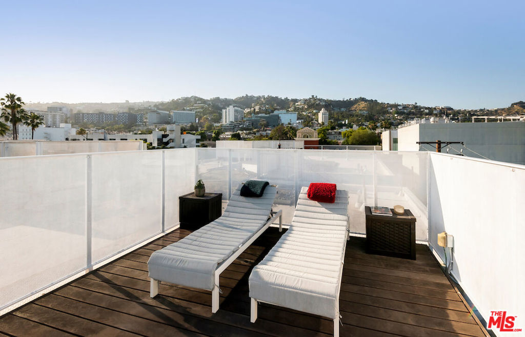 Welcome to 1030 Kings, a refined collection of 25 contemporary condominiums on historic Kings Road. Penthouse Residence 407 is a standout two-bedroom, two-bath home that reflects the building's thoughtful design and elevated finishes. This light-filled residence features ten-foot ceilings, expansive window walls, and an airy open-plan layout that flows effortlessly onto a private terracean ideal setting for morning coffee or evening gatherings. A spiral staircase leads to an expansive private rooftop deck with panoramic views of the Hollywood Hills, perfect for entertaining under the stars. The Bauformat kitchen is designed for both beauty and function, with a mobile waterfall island, raw wood cabinetry, and top-of-the-line Miele appliances. The serene primary suite includes a custom Closet Factory walk-in wardrobe and a spa-inspired bath clad in floor-to-ceiling marble, complemented by a Bauformat oak vanity and TOTO porcelain sink. Smart home features, in-unit laundry, and extra garage storage add convenience, while the building offers controlled access, gated tandem parking, a fully equipped fitness center, and two beautifully designed outdoor lounge areas with sweeping views. Designed by award-winning architect LOHA with interiors by MLH Design Group, Residence 407 blends luxury, style, and modern ease in one of West Hollywood's most desirable neighborhoods.