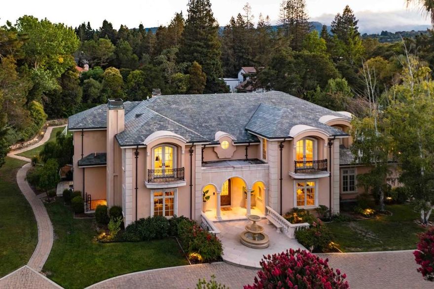 Tucked behind a gated motor court in one of Silicon Valleys most prestigious neighborhoods, this grand Atherton estate offers over 10,500 square feet of refined living. A column-framed arched entryway and front fountain set the tone for timeless elegance, with rich millwork, hardwood floors, soaring ceilings, and brilliant natural light throughout. Three expansive levels are connected by both staircase and elevator, featuring formal rooms, a walk-out family room, gourmet kitchen, and executive office. Six deluxe bedroom suites include a stunning primary with balcony and spa-inspired bath. The lower level is built for entertaining, with a theater, game room, wine cellar, tasting kitchen, and gym. Outside, the vast backyard invites relaxed living and future possibilities, plus a detached guest studio adds versatility. Enjoy air conditioning, two 2-car garages, and a location near Stanford, Menlo Park, and top schools including Las Lomitas (buyer to verify eligibility).