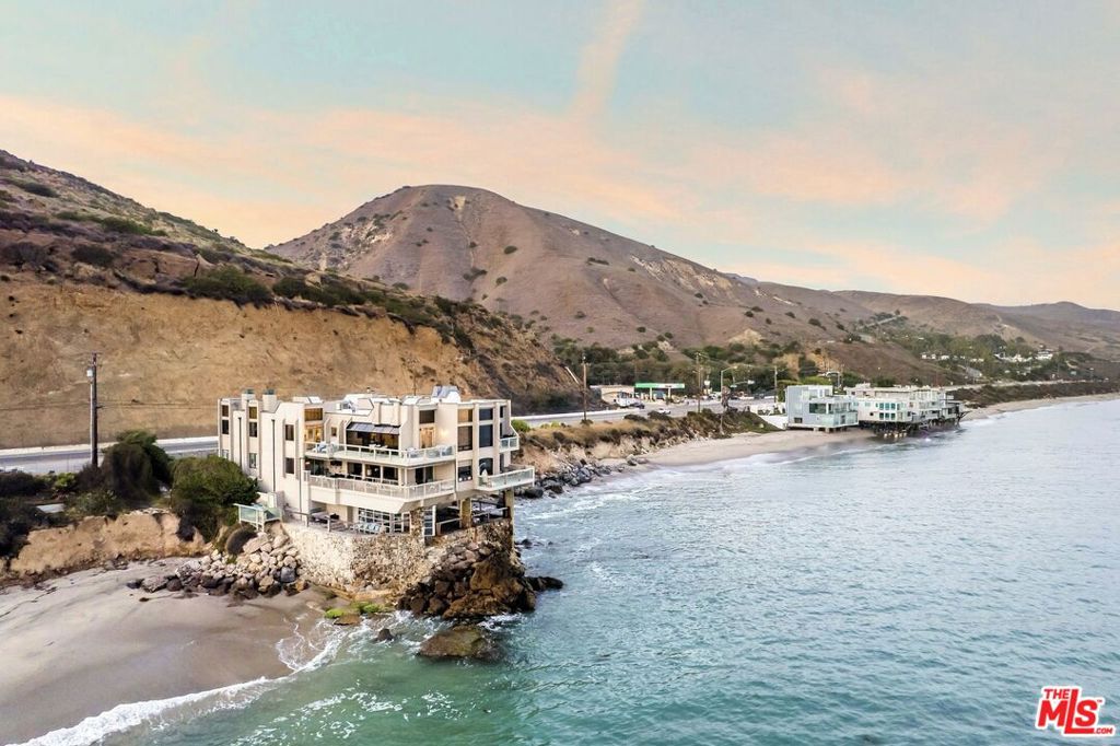 Set just north of Corral Canyon on Malibu's Pacific Coast Highway, this gated beachfront penthouse residence sits within a unique four-home building, blending privacy, inventive design, and uninterrupted ocean views. Designed by award-winning Malibu architect Michael E. Barsocchini, 26174 Pacific Coast Highway is a three-bedroom, two-bath, single-level home spanning 1,921 square feet, with no neighboring buildings and direct access to a rare, secluded stretch of sand. True to Barsocchini's style, the penthouse offers an open floor plan, double-height vaulted ceilings with skylights, and walls of glass that maximize natural light while framing sweeping ocean views. The kitchen captures the same dramatic vistas of the Pacific, bringing the ocean into daily living and entertaining. The primary suite features a cozy fireplace, walk-in closet, spa-like bath with soaking tub and shower, and French doors opening to a wraparound beachfront deck. Two additional bedrooms provide more ocean views, while a charming library nook with sliding ladder adds character. The guest bath stands out with its striking all-brick design, adding warmth and texture. Amenities include two gated garage spaces, guest parking, a sauna with ocean views, and a large entertaining deck- perfect for sunset dinners, weekend gatherings, or morning surf checks. Just minutes from Malibu Country Mart, Paradise Cove, Latigo's surf break, and Pepperdine University, this rare penthouse retreat delivers the essence of exclusive coastal living. Highlights of owning in this ideally located building include low HOA fees, direct beach access, and the intimacy of a small community compared to larger Malibu complexes- all with the rarity of a secluded beachfront shared with no other buildings- something even most estates priced over $20M cannot claim.