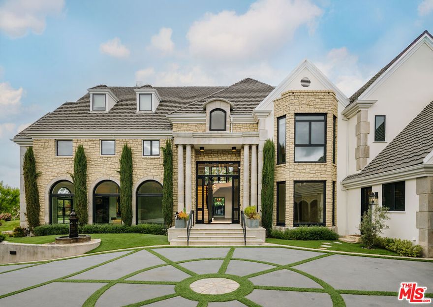 Welcome to 20608 Chatsboro Drive, a timeless estate in the heart of Woodland Hills that blends modern luxury with classic elegance. Set behind gates on a sprawling lot, this grand residence makes a bold statement with its circular motor court, stately columns, and manicured landscaping. Inside, a soaring two-story entryway sets the tone for the home's impressive scale and sophisticated finishes. Wide-plank wood and tile floors flow through expansive living spaces, including a formal living room with arched windows and a striking marble fireplace, and a coffered-ceiling family room with seamless indoor-outdoor flow. The chef's kitchen is a masterpiece, featuring waterfall stone countertops, custom cabinetry, and top-of-the-line appliances. The opulent primary suite offers a tranquil retreat with dual fireplaces, bay windows, and a boutique-style closet. Spa-inspired bathrooms throughout the home feature designer finishes, floating vanities, and backlit mirrors.Outdoors, resort-style amenities await, a sparkling pool and spa, fully equipped outdoor kitchen, stone fireplace, and a lighted full-size basketball court. A detached flex space provides the perfect studio, gym, or guest retreat. This estate is the ultimate blend of comfort, privacy, and entertaining power in one of the Valley's most coveted neighborhoods.
