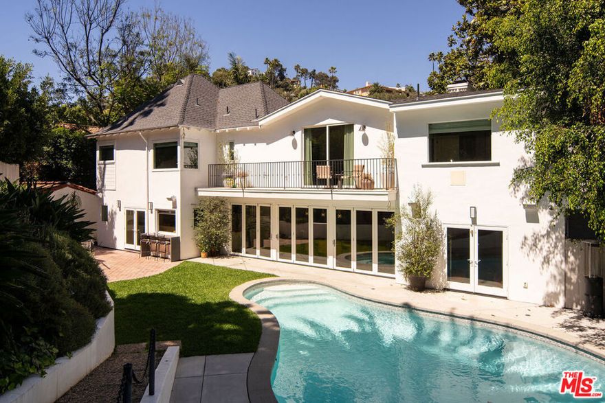 Welcome to this exquisitely reimagined 1938 residence, a timeless retreat nestled in the heart of Outpost Estates at the base of the Hollywood Hills. This designer-done estate masterfully blends Old Hollywood glamour with modern sophistication, offering a rare fusion of architectural integrity and contemporary luxury. Behindits romantic, historic faade lies a fully transformed interior, where no detail has been overlooked and no expense spared.The home unfolds across 4,207 square feet of refined living space, framed by natural textures and ultra modern finishes. A grand living room sets the tone with its striking Paonazzo Corchia marble fireplace, flowingseamlessly into an elegant dining area perfect for hosting. The chef's kitchen, with its own integrated coffee pantry, pass-through window and custom temperature-controlled wine cellar are ideal for curated entertaining.The spacious bedrooms all include custom designed closets, and with the six luxurious bathrooms, you're provided with flexibility for both family living and comfortable guest accommodations.A row of French doors open wide to reveal a resort-like backyard oasis, lushly landscaped and framed by mature palms and rose bushes. An outdoor kitchen with pizza oven, sparkling pool, fire pit, and expansive patios invite effortless indoor-outdoor living. Whether you're enjoying a quiet morning coffee or a lively evening under the stars, every corner of this estate feels like a curated escape.Additional highlights include the option to purchase the home fully furnished. With its mix of one of a kind vintage furniture, collectible contemporary, and bespoke pieces that are designed specifically to fit the space- It's a true turnkey opportunity. Set on an impressive 11,355-square-foot lot, the property offers a rare sense of privacy while remaining moments from the pulse of thecity.A captivating expression of historic charm and modern elegance, this Outpost Estates gem is more than a home - it's a lifestyle.