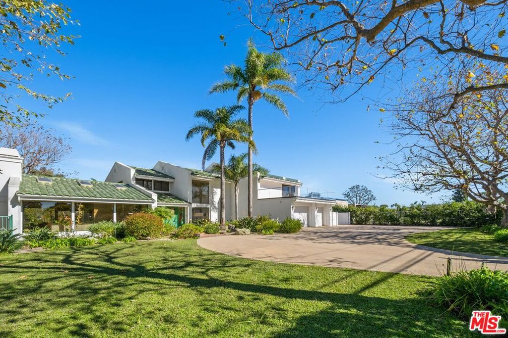 Set behind gates on a park-like 1.3-acre parcel atop Point Dume, this private estate offers a rare blend of natural beauty, thoughtful upgrades, and timeless California living. A canopy of sycamore trees and a circular motor court create a warm and welcoming arrival, leading to a light-filled residence spanning approximately 3,452 square feet with four bedrooms and three-and-a-half baths.The interior is awash with natural light, thanks to expansive windows and skylights that bring the outdoors in. At the heart of the home is a sleek, modern kitchen outfitted with Miele and Sub-Zero appliances, custom cabinetry, and clean-lined finishes an ideal setting for both everyday living and entertaining. The main level also includes a bedroom and full bath, a dramatic living room with soaring ceilings and a gas fireplace, a powder room, laundry room, and direct access to a spacious three-car garage.Upstairs, three additional bedrooms open to private patios with sweeping views across the treetops to the Pacific Ocean. The grounds are equally compelling a lush, thoughtfully landscaped garden filled with fruit trees, native California plantings, and towering Queen Palms that attract hummingbirds, butterflies, and other pollinators. Multiple patio areas with built-in fire pits offer elegant spaces for outdoor entertaining and quiet retreat.Additional features include a full-home water filtration system, central vacuum, abundant custom cabinetry, a meticulously maintained backup generator, and ample on-site parking. The expansive 59,241-square-foot lot offers both privacy and usability, just moments from the Point Dume Headlands, where hiking trails, panoramic views of the Queen's Necklace, and access to some of Malibu's most pristine beaches await.