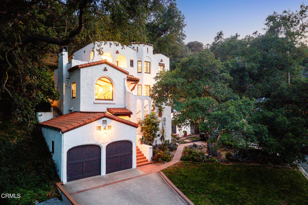 Delightfully poised within the tranquil Verdugo Woodlands neighborhood of Glendale, this refined 1928 Spanish Colonial Revival welcomes serene living within a thoughtfully composed 2,277 SF. Noted as one of the first homes to be built on San Luis Rey Dr., this architectural jewel has been lovingly preserved with original details throughout. Updated with preservation and cohesiveness in mind, the home welcomes modern living while maintaining a romantic and timeless aesthetic. With striking curb appeal, an arched entry staircase welcomes you to a landing above. Upon entry, hardwood floors skip trowel walls sweep the space. A step-down living room lies to the left, and offers the perfect space for rest and entertainment. With a vaulted and beamed ceiling, the airy room is accentuated by a picture window that permeates natural light, while granting treetop views of the hills beyond. Tastefully restored, a fireplace warms the space, with tile surround and wood block mantle. Built-in bookshelves flank a staircase that leads to an additional space, perfect for a home office or reading room. From the entry, a welcoming dining room opens from arch doorways into an additional eating room. The kitchen sits beyond and is complete with recent updates throughout including stainless steel appliances, custom cabinets, farm sink and built in wine refrigerator. Hidden within, a stacked laundry serves the house with function in mind. Completing the first floor, a guest bedroom and guest bath are located beyond the entry while giving private access to the back patio through French doors. The second floor is composed of an additional guest bedroom with a covered patio. An additional updated bathroom rests down the hall with stylish finishes. The primary suite lends quiet and spacious privacy with a cupola ceiling, sitting area and surrounding windows. Finishing off the retreat, a refined bathroom with double sinks, Custom cabinet and stone feature wall is lit from a skylight above. Enjoy breezy afternoons on the patio in the backyard while resting among the treetops. Close to Verdugo Park, Montrose and Oakmont Country Club.