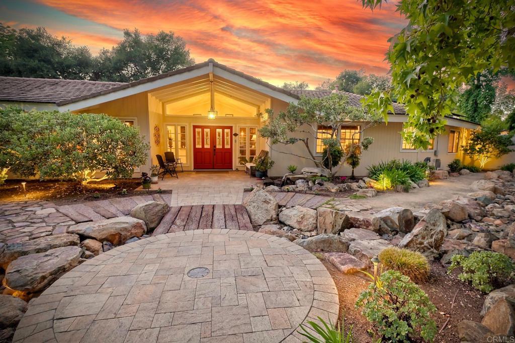 Experience elevated country living at 1285 Hidden Oaks Trail, nestled on a serene 1-acre estate in one of Vista’s most desirable communities. This single-story luxury retreat offers the perfect blend of sophistication, functionality, and resort-style amenities. Enter into a beautifully designed home where modern upgrades and timeless details shine. The chef’s kitchen is a culinary masterpiece, featuring a 6-burner stove, double oven with warming drawer, and a brand-new refrigerator purchased this year. Entertain effortlessly with a built-in wet bar featuring a refrigerator and upgraded surround sound speakers throughout the kitchen, living room, and outdoor pool area. Experience a true private oasis with a resurfaced pool (2023), a propane fire pit plumbed to the main tank, and professionally landscaped grounds with a rock waterfall and elegant outdoor lighting. This property is equipped with fully owned solar, dual air conditioners, a bonus structure attached to the main garage and an additional detached 2-car garage. The main garage is wired for 30-amp RV service and the separate 2-car garage with 220 power. Additional conveniences include two storage sheds, a wired alarm system, and atrium doors that open directly to the pool area. The primary suite features dual closets, including a secure wall safe in the primary closet. Guests will enjoy the spa-like bathrooms with two jetted tubs and one shower with 12 shower heads, including a rain shower head. The orchard boasts a variety of fruit trees, including orange, avocado, nectarine, mulberry, kumquat, plum, lemon, lime, grapefruit, pear, loquat, tangerine, fig, and berries, offering a farm-to-table experience right at home. Eight raised garden beds and a charming potting shed make gardening a delight.