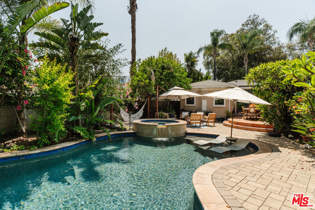 Incredibly redone, this prime Toluca Lake home features a thoughtfully designed renovation in the coveted pocket south of Riverside and east of Cahuenga. A large kitchen with a curved dining banquette and breakfast bar flows effortlessly into an expansive family great room, which opens to a lush backyard retreat with a stunning lagoon-style pool featuring a Baja shelf, waterfalls, and spa, along with a lounge area and outdoor dining space. The oversized primary suite offers a walk-in closet and a sit-down vanity and a stunning ensuite. Two additional luxurious bedrooms and a chicly renovated guest bath complement the home, while the grand formal dining and living rooms provide an array of entertaining options. Nestled on a quiet, tree-lined street just a short distance from the shops and restaurants on Riverside Drive and close to the Studios, the home retains its timeless charm with original details like glass block, curved architecture, and casement windows. Two fireplaces, an assortment of mature fruit trees, and a sprawling lawn add to its character, while solar panels provide modern efficiency.