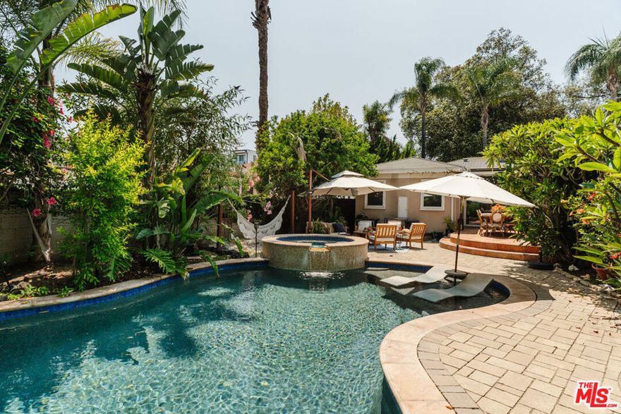 Incredibly redone, this prime Toluca Lake home features a thoughtfully designed renovation in the coveted pocket south of Riverside and east of Cahuenga. A large kitchen with a curved dining banquette and breakfast bar flows effortlessly into an expansive family great room, which opens to a lush backyard retreat with a stunning lagoon-style pool featuring a Baja shelf, waterfalls, and spa, along with a lounge area and outdoor dining space. The oversized primary suite offers a walk-in closet and a sit-down vanity and a stunning ensuite. Two additional luxurious bedrooms and a chicly renovated guest bath complement the home, while the grand formal dining and living rooms provide an array of entertaining options. Nestled on a quiet, tree-lined street just a short distance from the shops and restaurants on Riverside Drive and close to the Studios, the home retains its timeless charm with original details like glass block, curved architecture, and casement windows. Two fireplaces, an assortment of mature fruit trees, and a sprawling lawn add to its character, while solar panels provide modern efficiency.