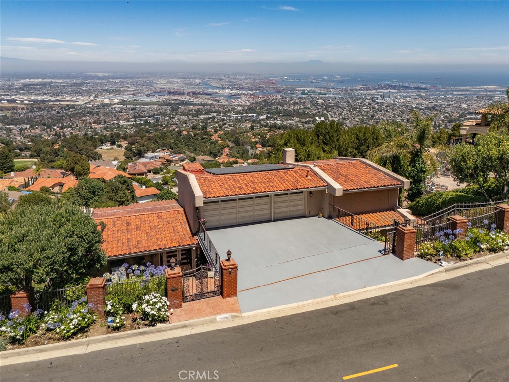 Perched majestically on the highest point of Miraleste Hills, this turnkey, move-in-ready estate is a serene sanctuary where elegance meets sophistication. Offering 4 expansive bedrooms and 6 updated bathrooms, this tri-level residence blends modern comfort with timeless design—set against an unforgettable sweeping views from Downtown Los Angeles and the iconic harbor to the San Gabriel Mountains and the glimmering shores of Newport Beach.From the moment you step through the front door, you are greeted by a sense of calm and grandeur. Expansive windows invite natural light to cascade through the home, framing mesmerizing vistas in every direction—sunlit mountains by day, twinkling city & LA port lights by night, and ever-changing scenes of ships arriving in port.Designed for both luxurious living and effortless convenience, the home features a sleek PVE pneumatic elevator connecting all three levels. The main floor showcases a refined formal living room, an elegant dining area, and a chef-inspired kitchen equipped with premium stainless steel appliances including a professional French door oven, gas cooktop, refrigerator, wine fridge, and under-counter drawer refrigerator. A cozy breakfast nook and tranquil master suite are perfectly positioned to capture the view. The lower level offers a spacious family room that opens to expansive wraparound balconies, where an extended terrace and jacuzzi create the perfect setting for entertaining or unwinding in style. Every bedroom is a private retreat with its own beautiful en-suite and generous closet, offering comfort, privacy, and stunning views. Additional highlights include a well-appointed laundry room with a deep sink, ample cabinetry, and a convenient laundry chute from the upper floor. Follow the charming red brick pathway to a lower-level flat pad, surrounded by mature fruit trees, ideal for gardening, a children’s play area, yoga studio, or private outdoor lounge. Sustainability meets sophistication with newer installed solar panels, a TESLA Powerwall, smart thermostat, Navien tankless water heater, and a top-tier York HVAC system with a newer AC unit—ensuring year-round comfort with modern efficiency. Securely tucked behind a gated driveway and lush landscaping, this property promises peace, privacy, and prestige. Welcome home where every sunrise is inspiring and every sunset is unforgettable.