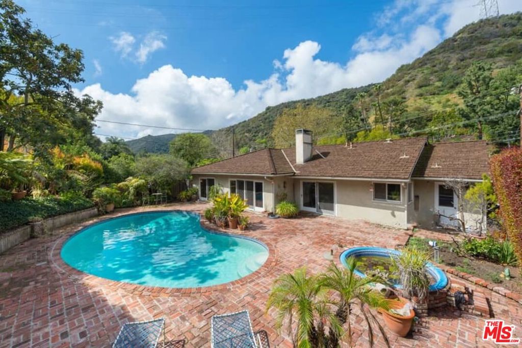 Custom California Ranch with Endless Potential in a Prime Setting. Perfectly positioned on a private corner lot and perched well above the street for privacy, this value-priced California Ranch invites you to bring your vision and create something truly special. Sunlight fills every space of this warm and welcoming home, which offers both generous square footage and exceptional indoor-outdoor flow. A broad double-door entry sets the tone, opening to a spacious country kitchen and adjoining family room, as well as a gracious formal living room, each anchored by a handsome brick fireplace and accented with vaulted, beamed ceilings. Expansive bay sliders frame serene views of the scenic patio, sparkling pool and spa, creating a seamless connection to the outdoors. The bedroom wing features a large primary suite with dual closets, a full bath with double vanities, and sliding doors to the poolside patio. Two additional bedrooms share a Jack-and-Jill bath, with the third bedroom offering the flexibility to serve as a private study or den, complete with dramatic pitched ceilings. Additional highlights include a utility room with direct garage access, an oversized two-car garage, peg-and-groove wood flooring, tile accents, recessed lighting, and a charming greenhouse window. This is an incredible opportunity to reimagine a timeless Ranch in a sought-after location, whether updating to suit your taste or expanding to maximize the lot's potential, the possibilities are endless.