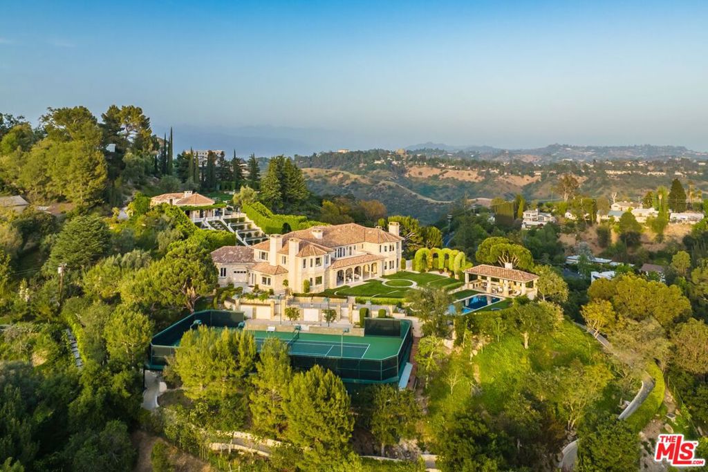 Perched at the pinnacle of Bel-Air on its own private mount, The Antelo View Estate is one of the rarest land finds in Los Angeles. This grand estate, spread across two APNs, this combined land offers unparalleled privacy behind double gates and features a sweeping motor court with commanding views of the city, mountains, and ocean. Recently transformed through an extensive remodel by renowned design-build teams, this estate is a masterpiece of luxury and elegance. The 6-bedroom, 9-bath main residence showcases grand-scale interiors with breathtaking vistas from both the first and second floors. Highlights of the lower wing of main residence include a cutting-edge movie theater and bar, staff quarters or massage room, wine storage, gym and steam shower. The newly constructed, custom kitchen is flawless, featuring white oak cabinetry, exquisite marble countertops, oversized sinks, Miele and Gaggenau appliances, a large walk-in pantry, an exquisite brass wine display, a grand fireplace, and a breakfast area with views. Upstairs, the second floor offers four generously sized bedrooms, while the primary suite stands out with dual baths, walk-in closets, a cozy fireplace, a private office, and a sprawling terrace. Two luxurious guest homes enhance the estate's allure. The upper two-story guest house offers 3,000 square feet of living space, including two bedrooms, three baths, a full kitchen, and a spacious living room with an oversized fireplace. French doors open to a garden terrace with a BBQ and expansive lawn. The lower guest home, located just below the tennis court, features a full kitchen, two baths, laundry room, and large walk-in closets, with wrap-around terraces and tranquil tree-top views. Additional features include a resort-style pool with a covered cabana, a fitness room, formal and informal living spaces, a golf cart path circling the entire estate, and a romantic loggia ideal for wine tastings. Unmatched in design, privacy, and luxury, The Antelo View Estate is a once-in-a-lifetime offering. THE ESTATE CAN BE DELIVERED FULLY FURNISHED.