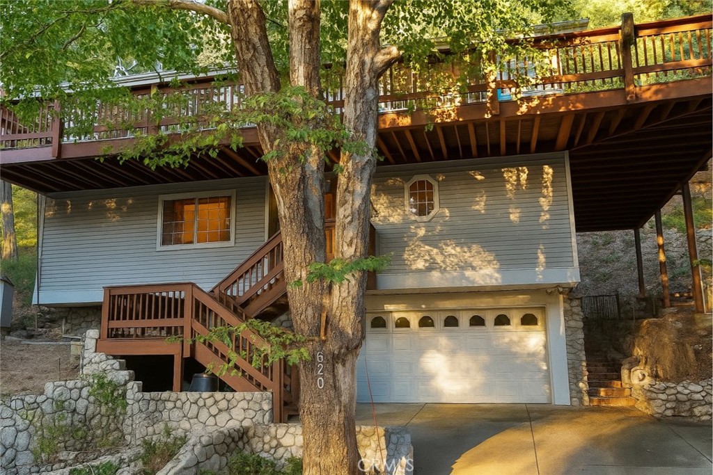 Welcome to your ultimate mountain retreat, just minutes from the tranquil shores of Lake Gregory. This lovingly maintained home showcases true pride of ownership, offering a spacious primary suite with a walk-in closet, a beautifully appointed bathroom, and direct access to a serene, half-acre backyard. Step outside to a rare and inviting outdoor setting featuring a natural year-round spring that flows through handcrafted stonework—creating multiple peaceful spots to relax and enjoy the soothing sound of running water. Elevated above the yard, a large Trex deck sits nestled among mature pine, cedar, and oak trees, complete with a built-in natural gas BBQ—perfect for outdoor dining and relaxation. Inside, you'll find a warm and welcoming living area with a granite fireplace, red oak flooring, and abundant windows that fill the space with natural light. The kitchen is designed with connection in mind, featuring a generous island and a seamless, open layout ideal for gathering with friends and family. Each of the two additional bedrooms is a private suite with its own bathroom and ample closet space, providing comfort and privacy for guests or family members. Additional features include a whole-house automatic generator, central air conditioning, an electric crane to lift firewood/heavy objects to and from top deck, motorized window coverings, centarl vacuum system, a walk-in pantry, stairlifts between every level, generous parking, a two-car garage, an outdoor storage shed, and more. You will not want to miss out on this rare gem!