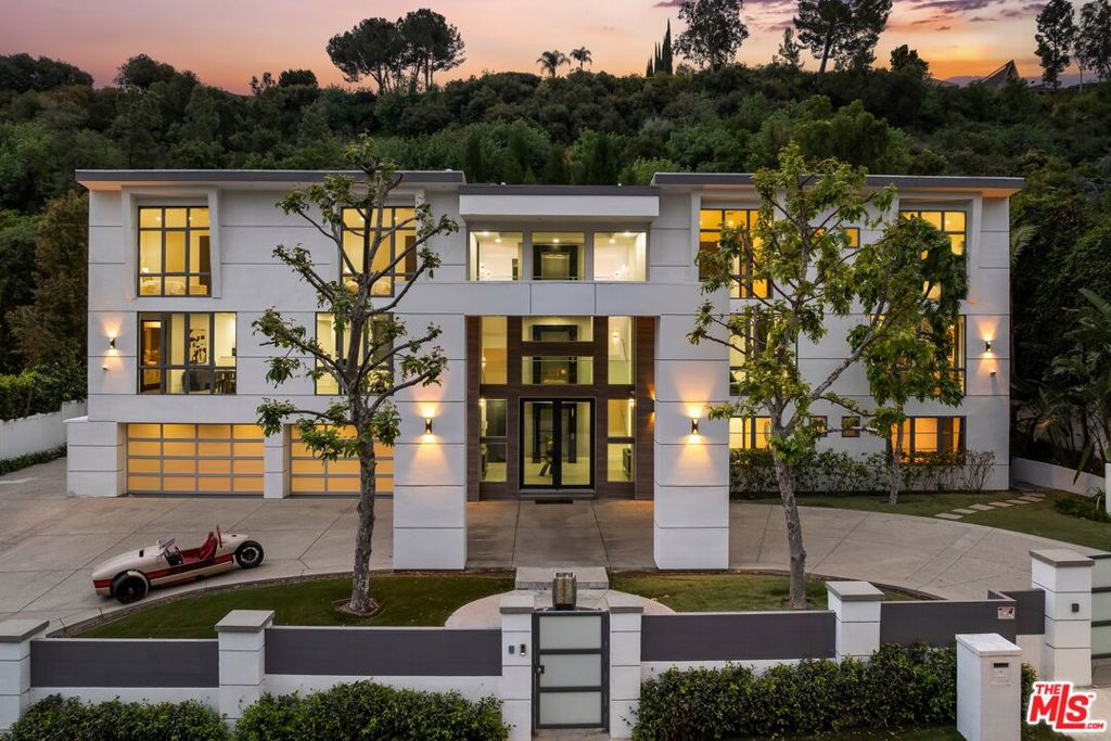 A rare offering of uncompromising luxury and privacy, this gated estate redefines resort-style living at the highest level. Tucked behind double gates and a grand motor court, the home welcomes you with a soaring three-story skylit foyer, an architectural prelude to the opulence that unfolds inside. A full-sized elevator and sweeping staircase guide you through expansive, light-filled interiors curated for both high-end entertaining and elevated everyday living. Every element has been designed with intention -from the private screening room and executive office to the 8-car showroom-style garage and generous ensuite guest quarters.The primary suite is a private retreat reminiscent of a five-star resort, featuring a serene sitting area, dual spa-inspired bathrooms, and boutique-style walk-in closets. Entertain with ease in the dramatic living room, anchored by a sleek fireplace and connected to an entertainer's lounge complete with a full wet bar and game area. A separate great room flows effortlessly into the chef's kitchen, outfitted with top-tier Wolf and Sub-Zero appliances, an oversized island, breakfast bar seating, dual dishwashers and sinks, custom walk-in pantry, and wine/beverage refrigeration. Step outside to your own secluded paradise, complete with a 70-foot cascading waterfall, 60-foot swimmer's pool, wraparound outdoor kitchen and bar, central fire pit, full sized basketball/tennis court and multiple luxe lounge areas. A one-of-a-kind estate where elegance, privacy, and world-class amenities converge.