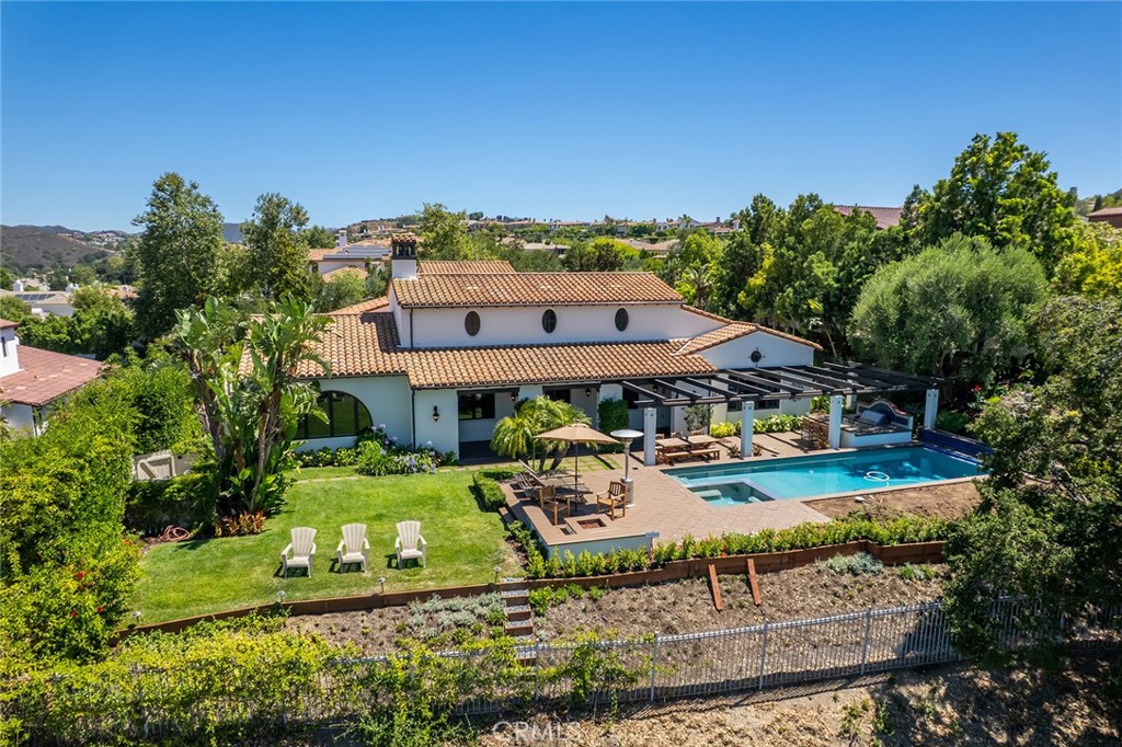 Inside the guard-gated Oaks of Calabasas, this single-level Spanish showpiece unites timeless Mediterranean character with modern comfort and unprecedented panoramic mountain vistas. An arched wrought-iron gate opens to a bougainvillea-lined courtyard. Beyond, vaulted beamed ceilings, terra-cotta floors and expansive picture windows fill the great room, formal dining area and chef’s kitchen with light. The kitchen anchors the home with pro-grade stainless appliances, an oversized island with bar seating, walk-in pantry and sunny breakfast nook. A private bedroom wing hosts an indulgent primary retreat featuring a soaking tub, large shower, water closet, dual vanities and a boutique-style walk-in closet. Three additional en-suite bedrooms flank a generous bonus/game room, plus a maids quarters and a separate courtyard-facing room flexes easily as an office, library or gym. A separate, private, dedicated home theater, caters to movie nights. Glass doors usher you to the resort-style backyard: pool, spa and multiple lounge and dining patios set against mountain views—ideal for effortless indoor-outdoor living. Residents enjoy top-tier community amenities: clubhouse, tennis and sport courts, Olympic-size pool, spa, professional gym and more. Moments from The Commons’ boutiques, dining and theaters and served by the acclaimed Las Virgenes School District, this property delivers elevated suburban living with city conveniences close at hand.