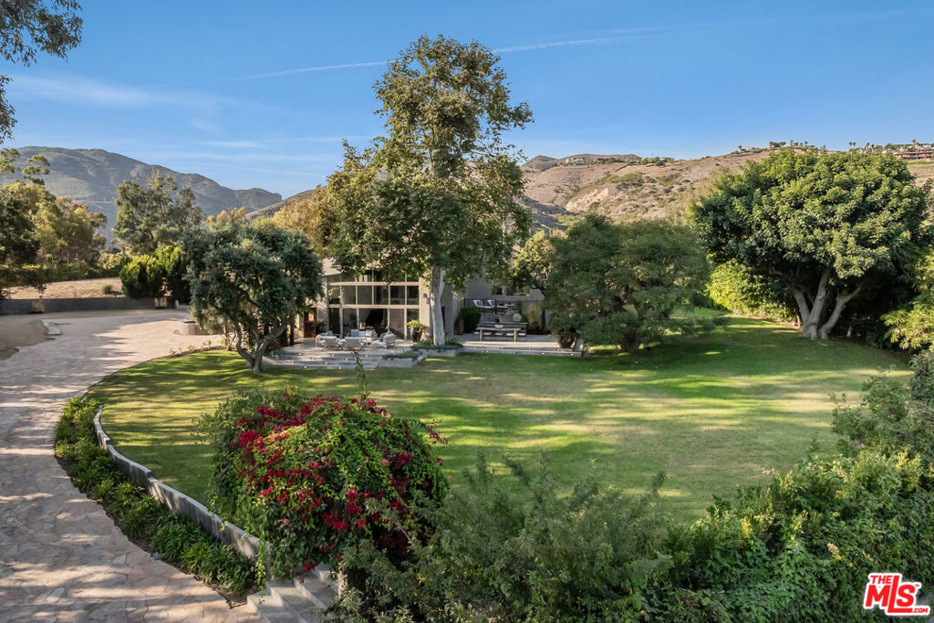 Tucked within Malibu's coveted Ramirez Canyon, just moments from the iconic shoreline of Paradise Cove, this privately gated estate offers the rare balance of seclusion, natural beauty, and coastal sophistication. Set on a sprawling one-acre lot, the property is framed by ancient oak groves and meandering creeks, creating an atmosphere that feels tranquil yet remains moments from one of California's most celebrated beaches.Beyond the iron property gates, expansive open grounds unfold to flat lawns, broad entertaining terraces, and Pacific views. The residence, designed with both style and function in mind and arranged with a thoughtful sense of flow of four bedrooms and four and a half baths, creates a natural rhythm between indoors and out.A dramatic entryway leads into soaring, open-concept living and family rooms, where natural light shines through floor-to-ceiling windows and soaring ceilings frame ocean and verdant landscapes. The chef's kitchen, seamlessly connected to the family room, is tailored for both relaxed gatherings and elevated entertaining. Each of the bedrooms, generously sized and paired with en suite bathrooms, offers refined luxury and comfort. Outdoors, generous patios provide the perfect backdrop for sunset dinners, weekend lounging, or hosting with ease. A large motor court ensures ample guest parking, complemented by an attached 2-car garage. Residents also enjoy exclusive access to Paradise Cove Beach, complete with a private parking pass, enhancing the convenience of Malibu living. More than a residence, this is a retreat: where the elements of ocean, grove, and architecture come together in quiet harmony, capturing the essence of coastal California living at its most refined. Plans for 592 sqft pool available upon request.