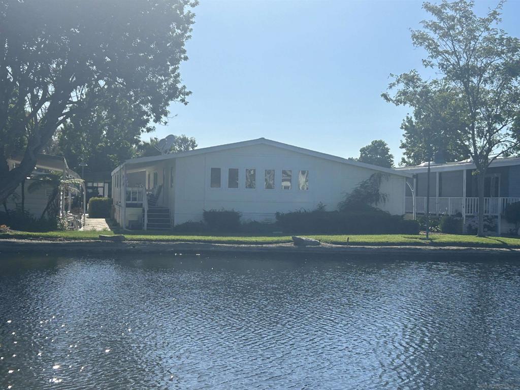 Laguna Vista Estates – Discover Coastal Living with Comfort, Style, and Community Amenities! Nestled within a sought-after gated 55+ community in Oceanside, this impeccably maintained 2-bedroom, 2-bath manufactured home offers approximately 1,440 sq ft of open-concept living with picturesque water views. Built in 1983, the residence features inviting living spaces with a blend of carpet and low-maintenance vinyl flooring, a functional kitchen equipped with modern appliances, and a spacious primary suite. Additional highlights include in-unit laundry, a 2-car covered carport, and tranquil lakeside scenery ideal for relaxation or entertaining. Laguna Vista Estates provides premium lifestyle amenities: meandering walking paths, serene lakes, greenbelts, a clubhouse, pool, spa, and year-round social events. With no property taxes, residents enjoy financial ease alongside vibrant community living. Minutes from beaches, dining, medical facilities, and shopping, this property presents a rare opportunity to own in one of North County’s most desirable mobile home parks. Ideal for buyers seeking affordability, active living, and coastal charm.