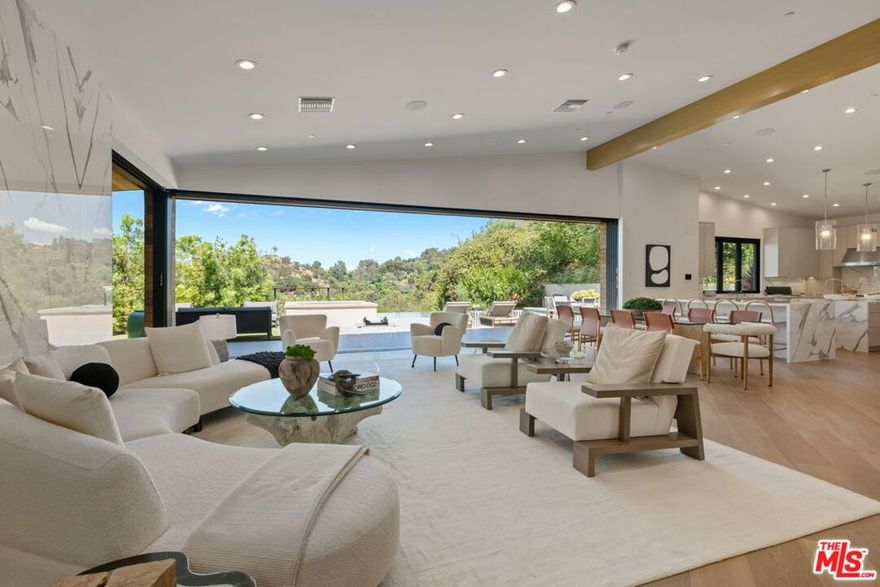 A brand-new single-story masterpiece, perfectly situated on a quiet cul-de-sac just north of the prestigious Trousdale Estates. Surrounded by beautiful trees and serene canyon views, this contemporary residence offers an exceptional blend of luxury, comfort, and sophistication. Designed with a seamless open floor plan and effortless indoor-outdoor flow, the living room boasts floor-to-ceiling automated sliding glass doors that open to a private backyard oasis with an infinity pool, spa, and waterfall. The expansive great room unites the living, dining, and chef's kitchen, featuring Miele appliances, dual sinks and ovens, two dishwashers, built-in espresso/coffee maker, microwave, and a refrigerator and freezer. A generous island and elegant European wood floors enhance the home's refined design. Offering 6 ensuite bedrooms and 9 bathrooms, the home provides unparalleled comfort for both family and guests. The media room, complete with a wide electric fireplace can be closed for privacy or opened to the main living area. The grand primary suite is a sanctuary, featuring a cozy seating area, private patio, and a stunning pearl onyx double-sided fireplace. It is complemented by two luxurious bathrooms with a soaking tub and steam shower complete this extraordinary retreat. Additional highlights include a temperature-controlled glass wine room, Sonos Arc sound system, and the finest finishes throughout. A true entertainer's dream, this residence exemplifies modern luxury at its finest.
