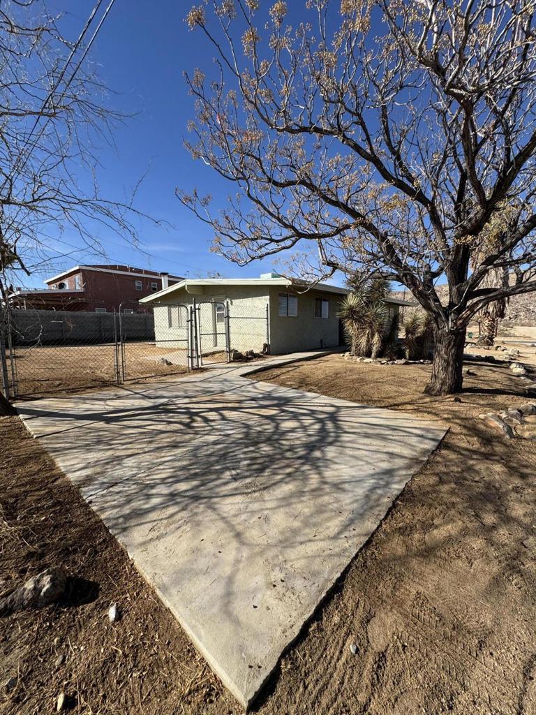Desirable mid-century flat roof design perched on a foot hill in the hip and trendy Joshua Tree Village. Spacious 3 bedrooms and 1.5 bath home on a sizable 7,475 sf corner lot. Open layout provides a large living room ideal for entertaining. Wood stove with brick hearth is complemented by white Terra Cotta tile. Roomy dining area leads to the sizable kitchen with abundant cabinet space, long counters, dual basin sink, dishwasher, stove, microwave and refrigerator. Hallway with built-in cupboards. Bathroom with new walk in shower, vanity. Master bedroom with washer and dryer closet. cabinetry, and second closet with mirrored sliding door. Office off master bedroom. Two more generous sized bedrooms. Attached garage. Glass slider in the living room leads to the backyard concrete slab patio with sun shade sale cover, block pavers and firepit. Privacy wall and chain-link fencing. Additional driveway with double d gate allows for RV access. Vistas of hills dotted with boulders and distant mountains. Just down the hillside is the popular JT Village with organic restaurants, cafes, bars and the farmers market. 6 miles to the Joshua Tree National Park entrance. About 3 million tourists visit the park annually. Great vacation area. 35 miles to Palm Springs. Very popular vacation area. 128 miles to Los Angeles. More celebrities, artists, and musicians are now calling Joshua Tree home than ever before. Don't Wait! - Call Now! Staged photos are AI generated.