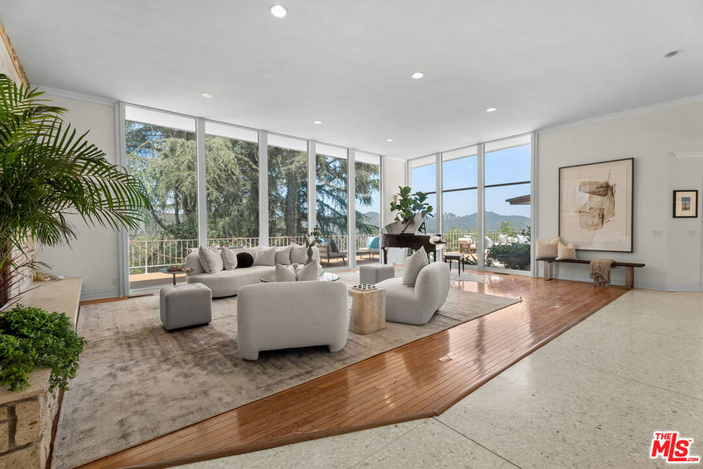 Tucked away at the very end of Upper Stone Canyon Road in prestigious Bel Air just beyond the iconic Bel Air Hotel this stunning mid-century modern estate offers a private and serene escape. Surrounded by lush landscaping, the home boasts sweeping views of the canyon and reservoir, creating a breathtaking natural backdrop. A gated entrance and an elegant bridge over a custom pool and spa welcome you into a sophisticated retreat designed for seamless indoor-outdoor living. Inside, you'll find an airy open layout with dramatic high ceilings and floor-to-ceiling glass that blurs the line between the interiors and the tranquil outdoor setting. Perfect for both everyday living and grand entertaining, the property features an expansive deck with a gas fire pit, a resort-style pool with intricate mosaic tilework, a spa with a cascading rock waterfall, and multiple spaces for relaxation including a family room, den, convertible office, and formal dining room.The primary suite offers a true sanctuary experience with generous closet space, a luxurious bath with skylights, and unobstructed panoramic views. Fully renovated throughout, the home features brand-new bathrooms and a gourmet chef's kitchen equipped with premium stainless-steel appliances and ready for immediate move-in.
