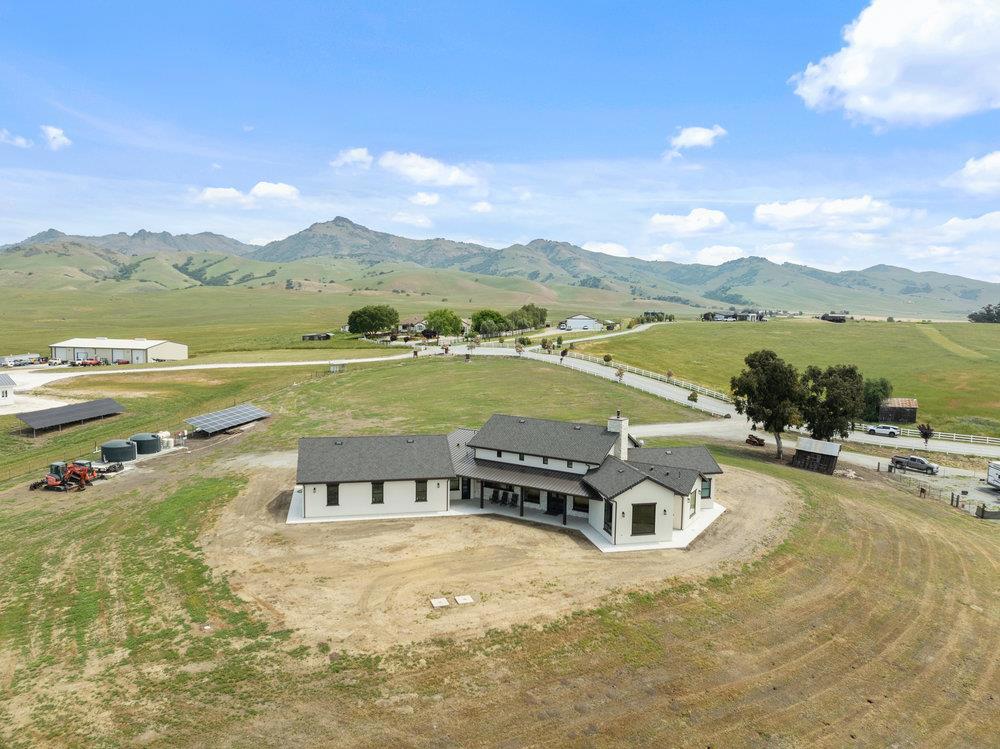 This newly built 2,592 square foot custom home sits behind an automatic gate on approximately 4.6 acres of San Benito County real estate, offering breathtaking views of the surrounding mountain range and city lights. Step inside to discover a spacious, modern interior featuring high vaulted ceilings that enhance the sense of openness and light. The heart of the home is in the large kitchen, designed with a massive island; perfect for entertaining and family gatherings. The living room seamlessly transitions to the outdoor patio through impressive folding doors, creating an ideal indoor-outdoor living experience. The outdoor patio is complete with a large cement pad, fireplace, and partially finished outdoor kitchen area. There is a second septic system for an ADU with services stubbed to a building area and a set of plans. There is a shop and an additional rv area stubbed with power, water, and septic hookups. Solar is owned.