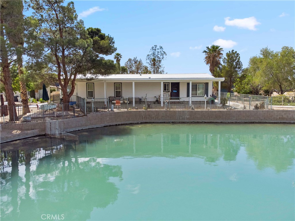 Life is better at the lake!! This 1.5 acre parcel located in the beautiful cove of Lake Jodie offers great views of the lake on an expansive corner lot that is fully fenced. The manufactured home is on permanent foundation with a covered front and back porch that is perfect for spending time outside enjoying the lake. Step inside the home and you have a laundry/utility room with washer/dryer hook-ups, a kitchen area that is open to the dining room and large living room with views of the lake. The primary bedroom has an en-suite bathroom with double sinks, soaking tub and walk in shower. The property has many mature palm trees and other shade trees. Besides amazing views, and a lakeside home, this property also features a large 40x80 metal shop with a roll up door that is perfect for working on projects and storing boats, jet skis or UTV's. And if that wasn't enough there is also an RV storage building and several outbuildings that can be used for overnight guests and containers for ample storage. This property is a MUST SEE! Lake Jodie is located in Newberry Springs, a 15 minute drive from Barstow and only a few miles from Interstate 15. The common area of Lake Jodie offers residents a community space for BBQ's, a boat launch, playground, and designated swimming area. Come out and see all that Newberry Springs has to offer, if you are looking to escape from the city and bring your water and desert toys, this is your HOME! **Septic has been inspected and certified, brand new leach line installed!