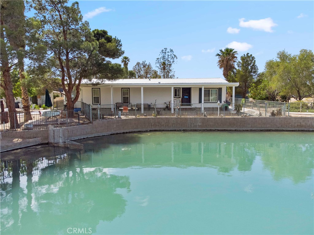 Life is better at the lake!! This 1.5 acre parcel located in the beautiful cove of Lake Jodie offers great views of the lake on an expansive corner lot that is fully fenced. The manufactured home is on permanent foundation with a covered front and back porch that is perfect for spending time outside enjoying the lake. Step inside the home and you have a laundry/utility room with washer/dryer hook-ups, a kitchen area that is open to the dining room and large living room with views of the lake. The primary bedroom has an en-suite bathroom with double sinks, soaking tub and walk in shower. The property has many mature palm trees and other shade trees. Besides amazing views, and a lakeside home, this property also features a large 40x80 metal shop with a roll up door that is perfect for working on projects and storing boats, jet skis or UTV's. And if that wasn't enough there is also an RV storage building and several outbuildings that can be used for overnight guests and containers for ample storage. This property is a MUST SEE! Lake Jodie is located in Newberry Springs, a 15 minute drive from Barstow and only a few miles from Interstate 15. The common area of Lake Jodie offers residents a community space for BBQ's, a boat launch, playground, and designated swimming area. Come out and see all that Newberry Springs has to offer, if you are looking to escape from the city and bring your water and desert toys, this is your HOME! **Septic has been inspected and certified, brand new leach line installed!