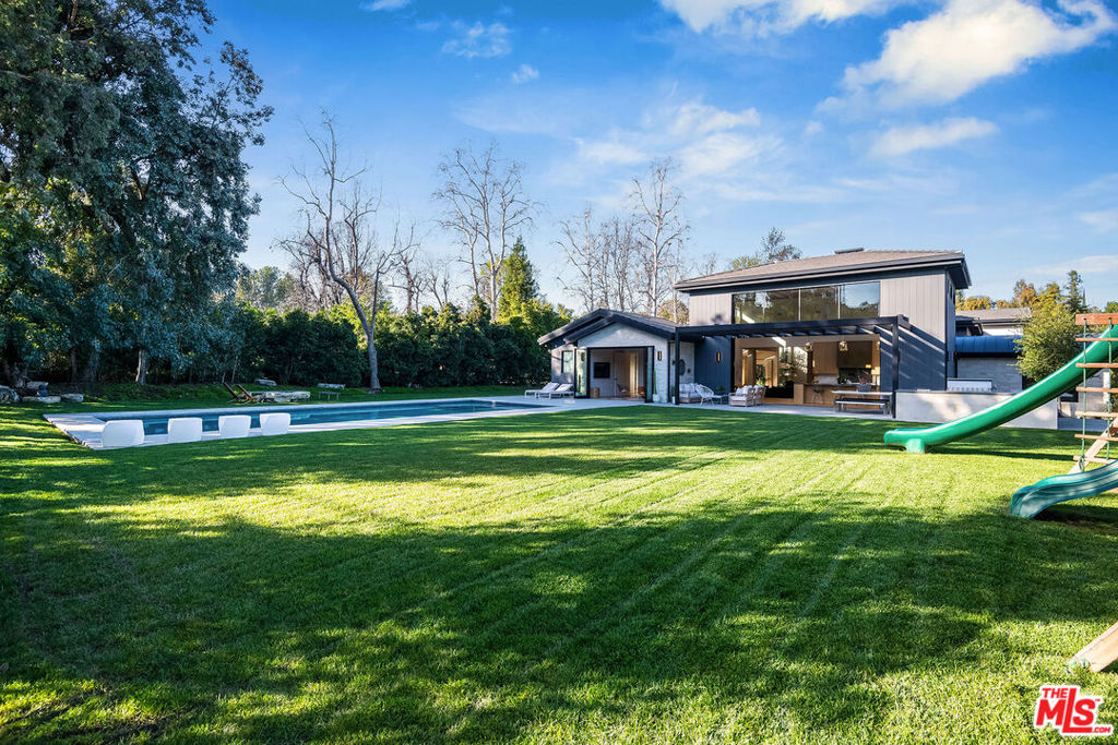 A Hidden Hills Rarity Expansive Single-Level Luxury with a One-of-a-Kind Subterranean Showroom!! Opportunities like this are exceedingly rare in Hidden Hills where nearly 11,000 square feet of refined living space unfolds primarily on a single level, creating an unparalleled sense of openness and grandeur. Set on over an acre of lushly landscaped grounds, this estate is a masterpiece of architectural design, blending effortless elegance with modern comfort. Stepping inside, you're greeted by soaring wood-paneled ceilings reaching up to 18 feet, amplifying the home's airy, sunlit interiors. Designed for both sophisticated entertaining and everyday ease, the open-concept floor plan seamlessly connects vast living and dining areas, all enhanced by meticulous craftsmanship and high-end finishes. A state-of-the-art private theater offers an immersive cinematic experience, while the magnificent primary suite tucked into its own private wing boasts dual spa-like baths and expansive walk-in closets, creating a true sanctuary of serenity. Yet, perhaps the most remarkable and extraordinarily rare feature of this estate is its massive subterranean garage, an automotive collector's dream. With the ability to accommodate 10+ vehicles, this secure, climate-controlled showroom is a hidden gem, offering the ultimate in privacy, protection, and presentation for prized automobiles. Overlooking this striking space is a glass-walled gym, executive office, or lounge, ensuring every inch of the home is designed with intention and luxury in mind. A separate guest house with a private entrance completes this exceptional property, providing the ultimate retreat for visitors or staff. Outdoors, a resort-style paradise awaits. Impeccably manicured grounds feature rolling lawns, a professional-grade putting green, two fire pits, a swimmer's pool, and a fully equipped outdoor kitchen, creating the perfect setting for both lavish entertaining and serene relaxation. This estate is truly one of the most unique offerings in Hidden Hills a rare fusion of grand-scale, single-level living and a world-class subterranean garage, setting a new standard for luxury.